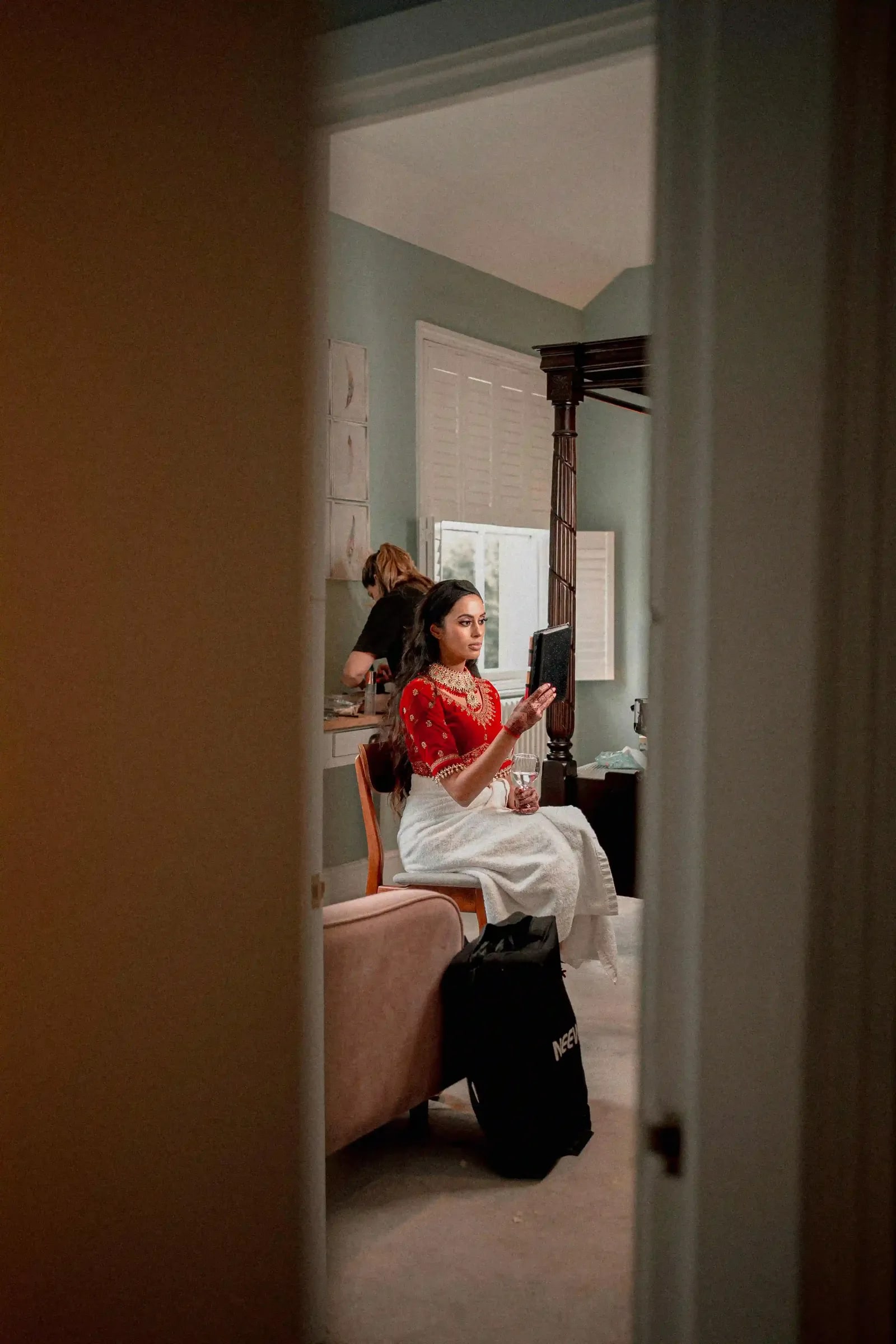 Bride getting ready, seen through a doorway in the bedroom before the ceremony
