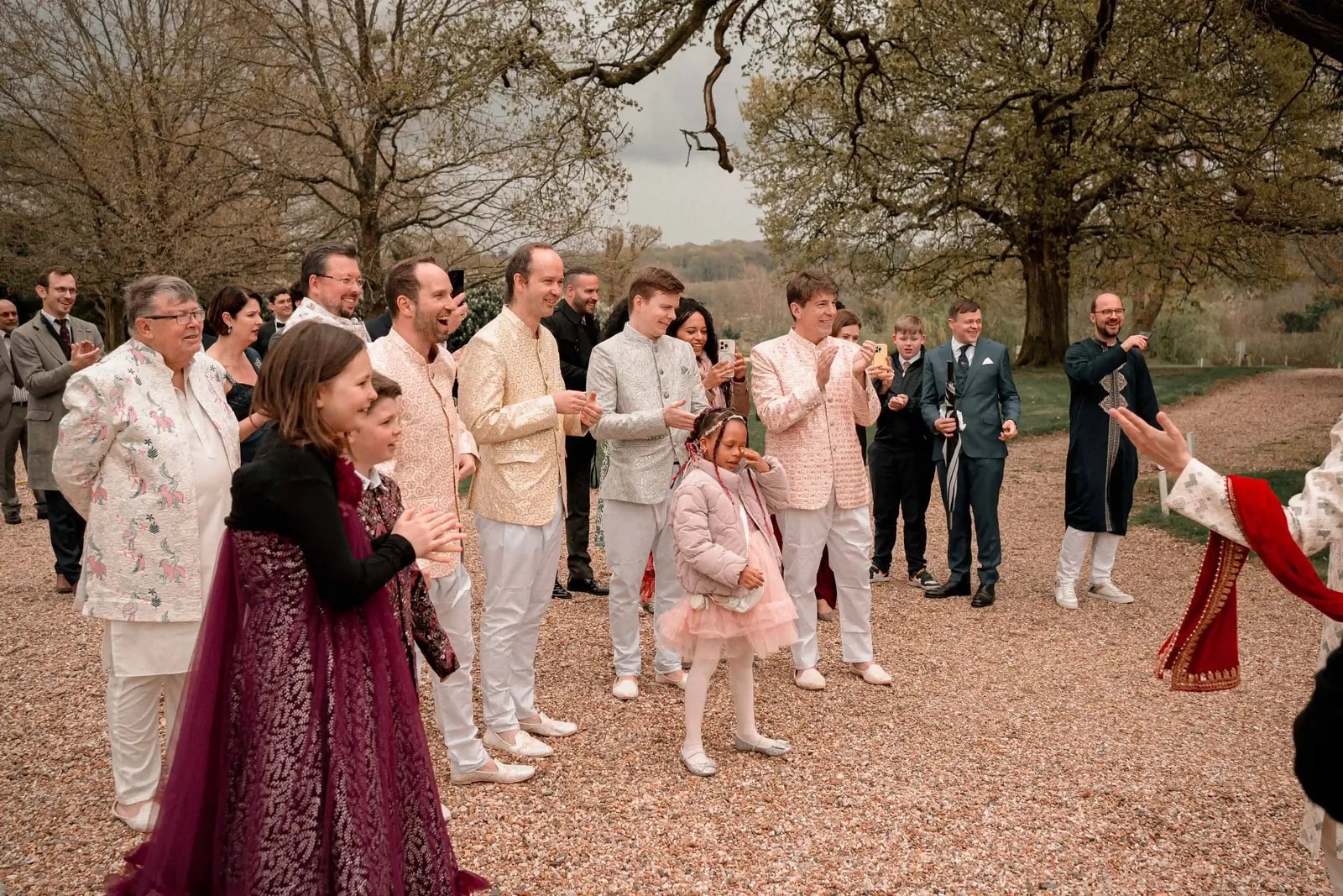 Guests gathered on the drive under bare trees, laughing together