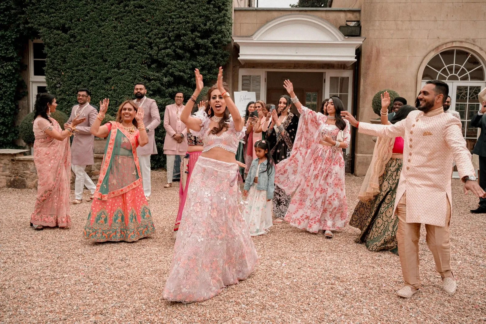 Guests dancing on the drive in pinks and pastels as the party arrives