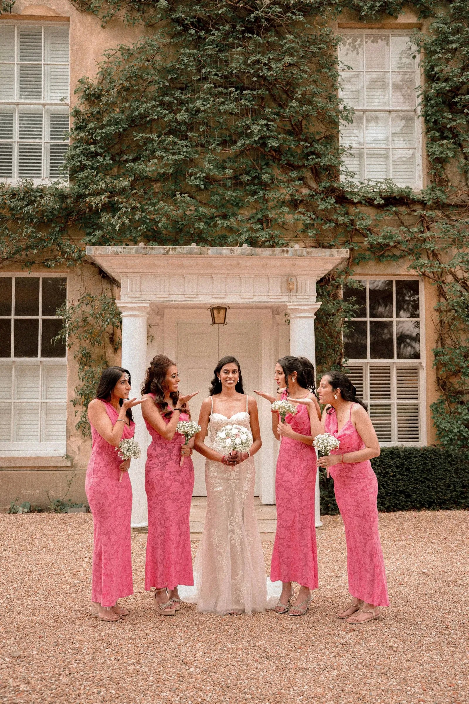 Bride and her five bridesmaids with bouquets in the doorway of the house