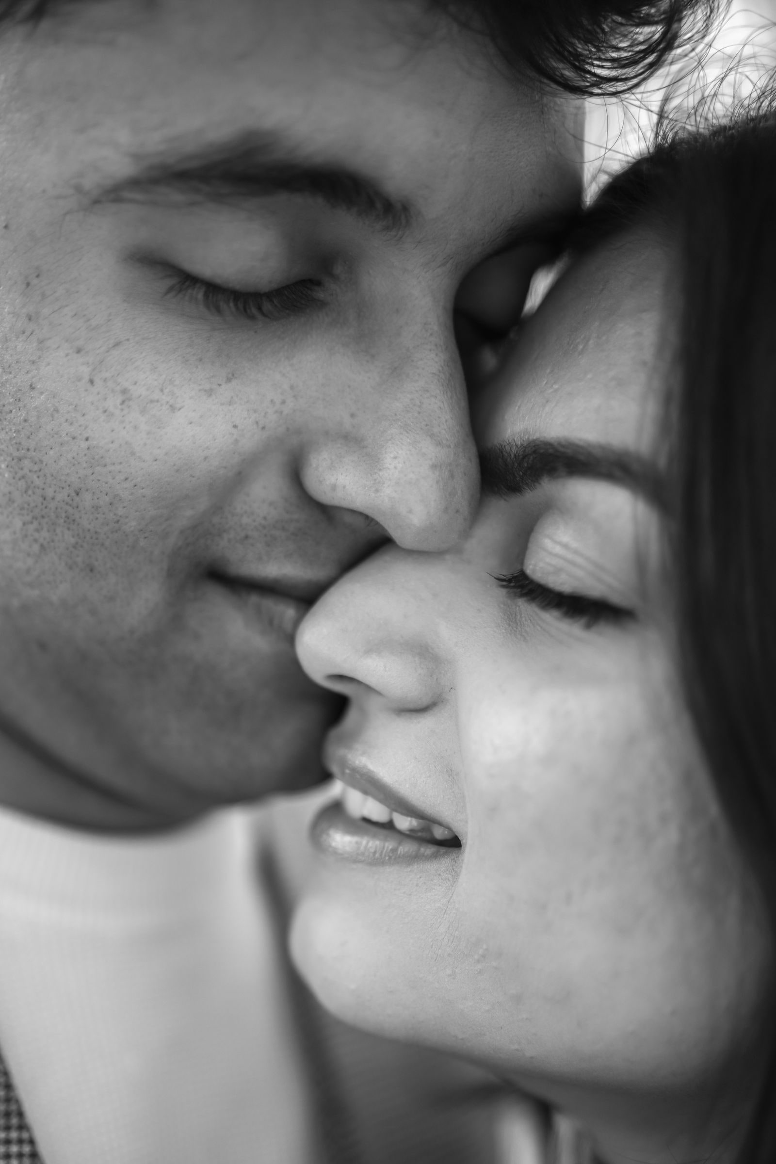 Close portrait of the couple cheek to cheek with their eyes closed, in black and white