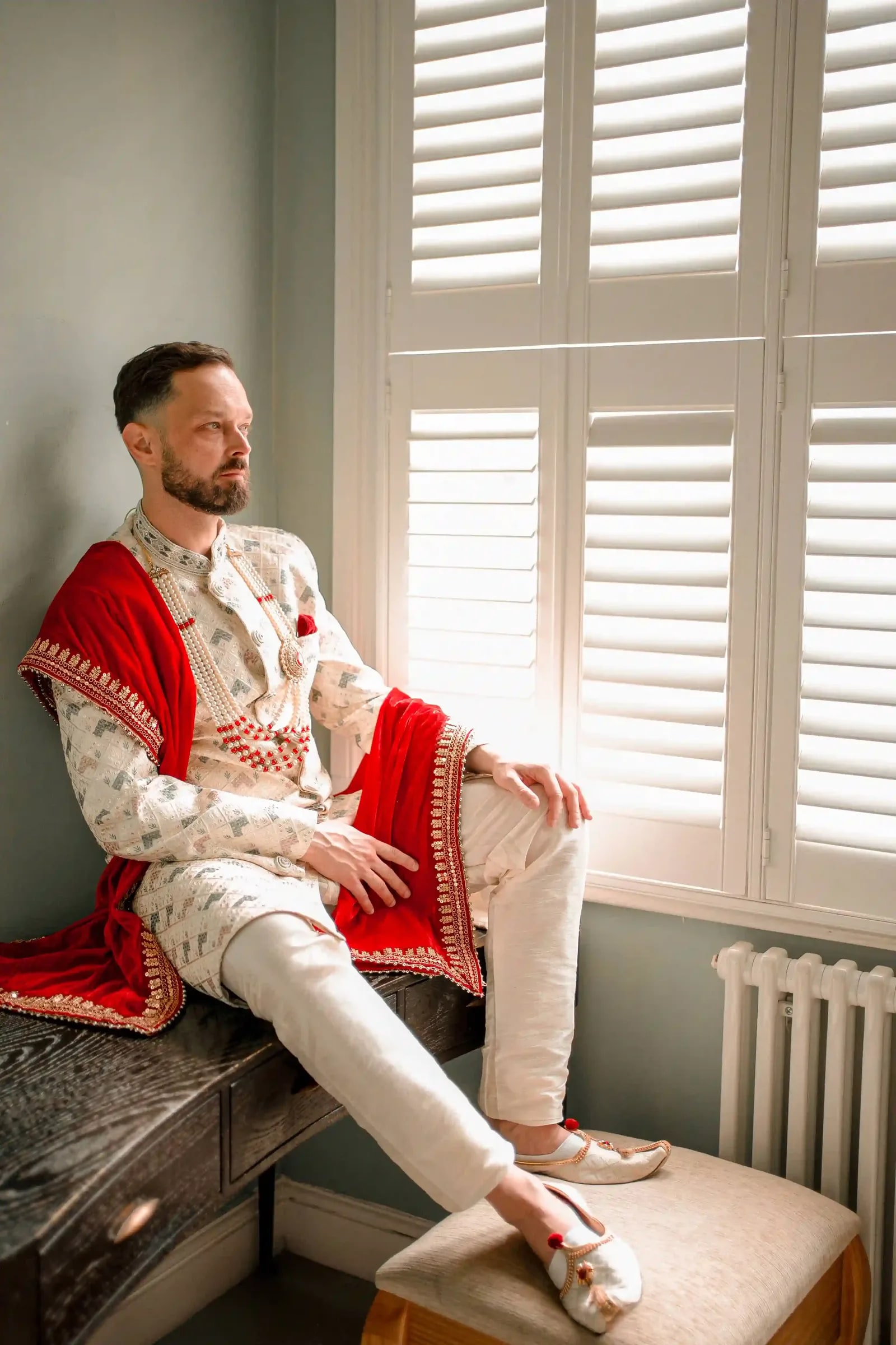 Groom seated on a window bench in the morning light before the ceremony