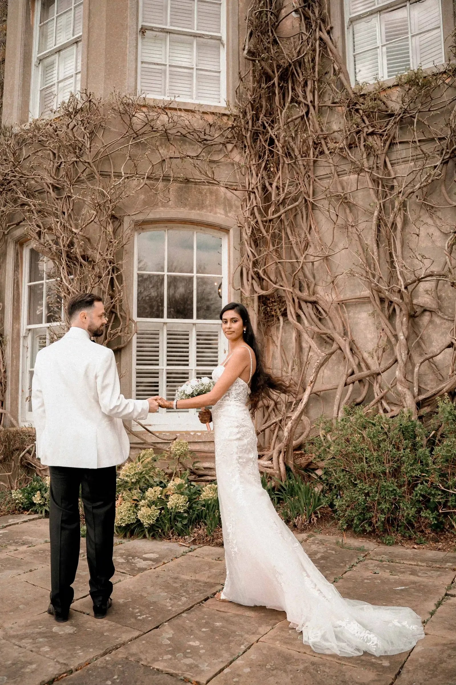 Groom turning his bride by the hand on the terrace, her train sweeping the stone
