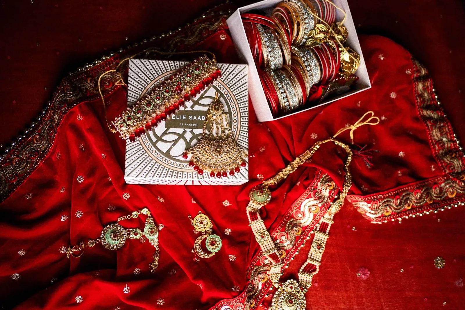 The bride's jewellery and bangles laid out on her red lehenga before she dresses