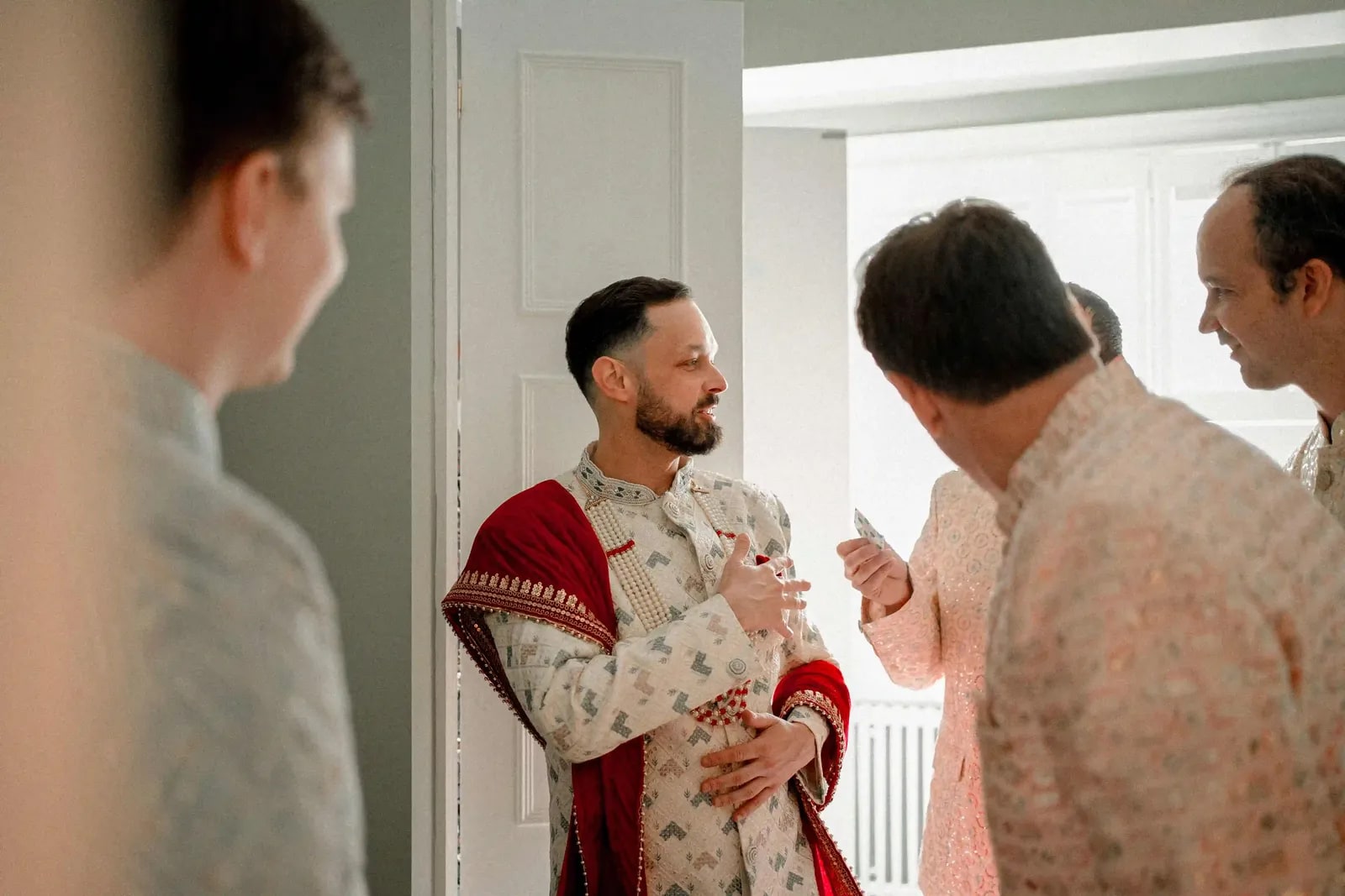 Groom greeted by guests in a doorway before the ceremony