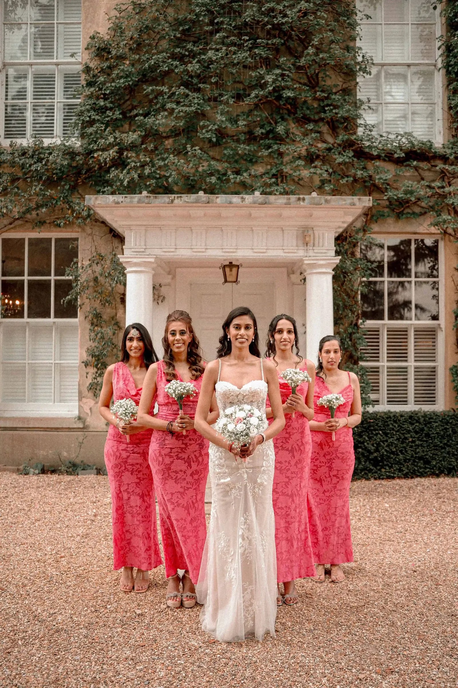 Bride and bridesmaids walking towards the camera across the gravel