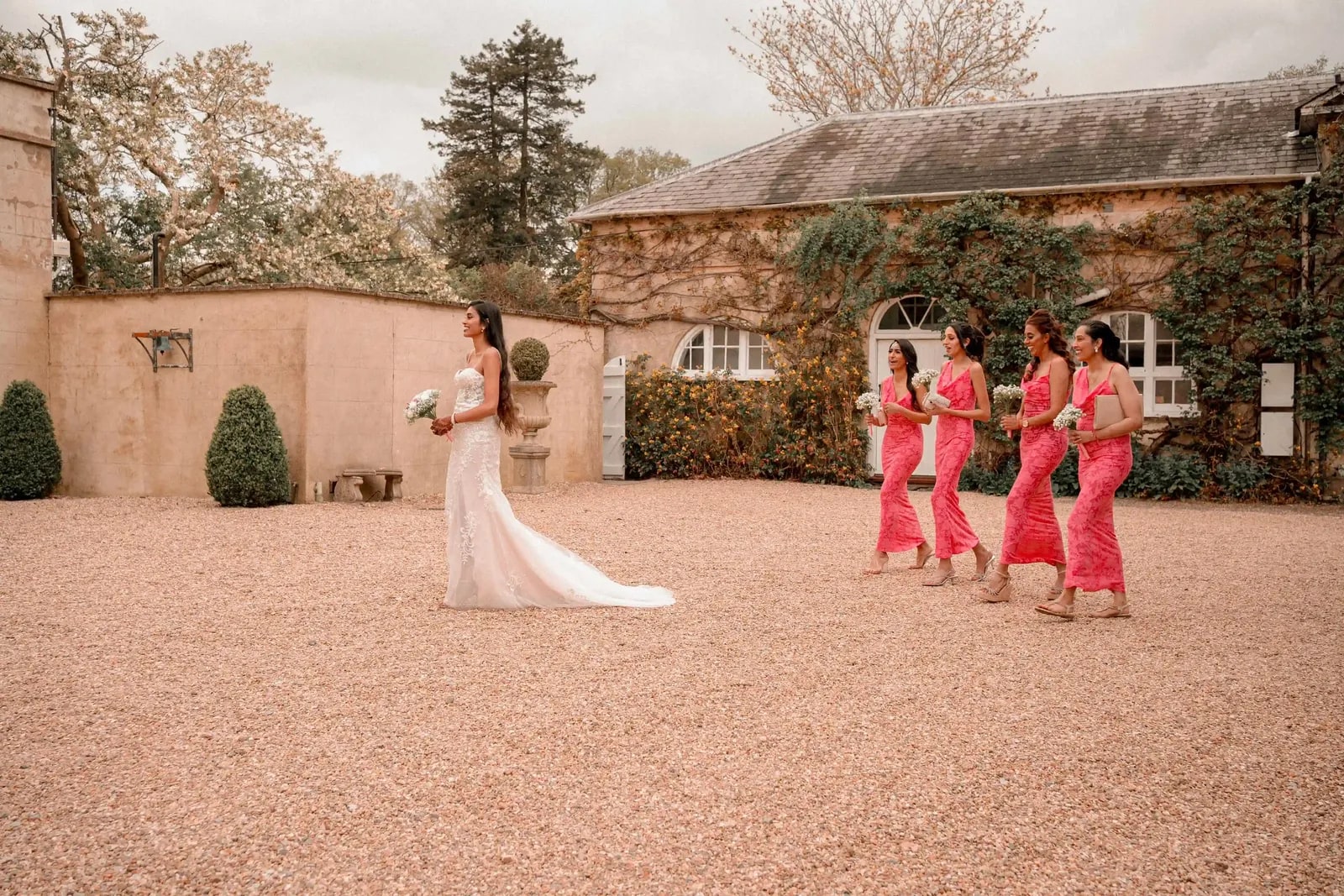 Bride walking away across the courtyard, bridesmaids following behind