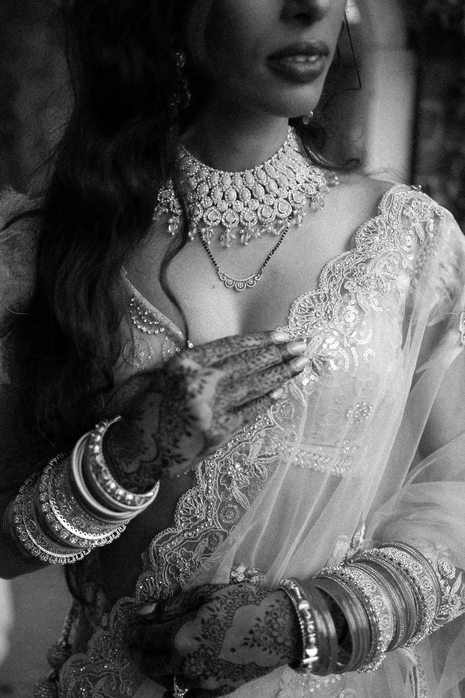 Close view of the bride's necklace, bangles and hennaed hands, in black and white