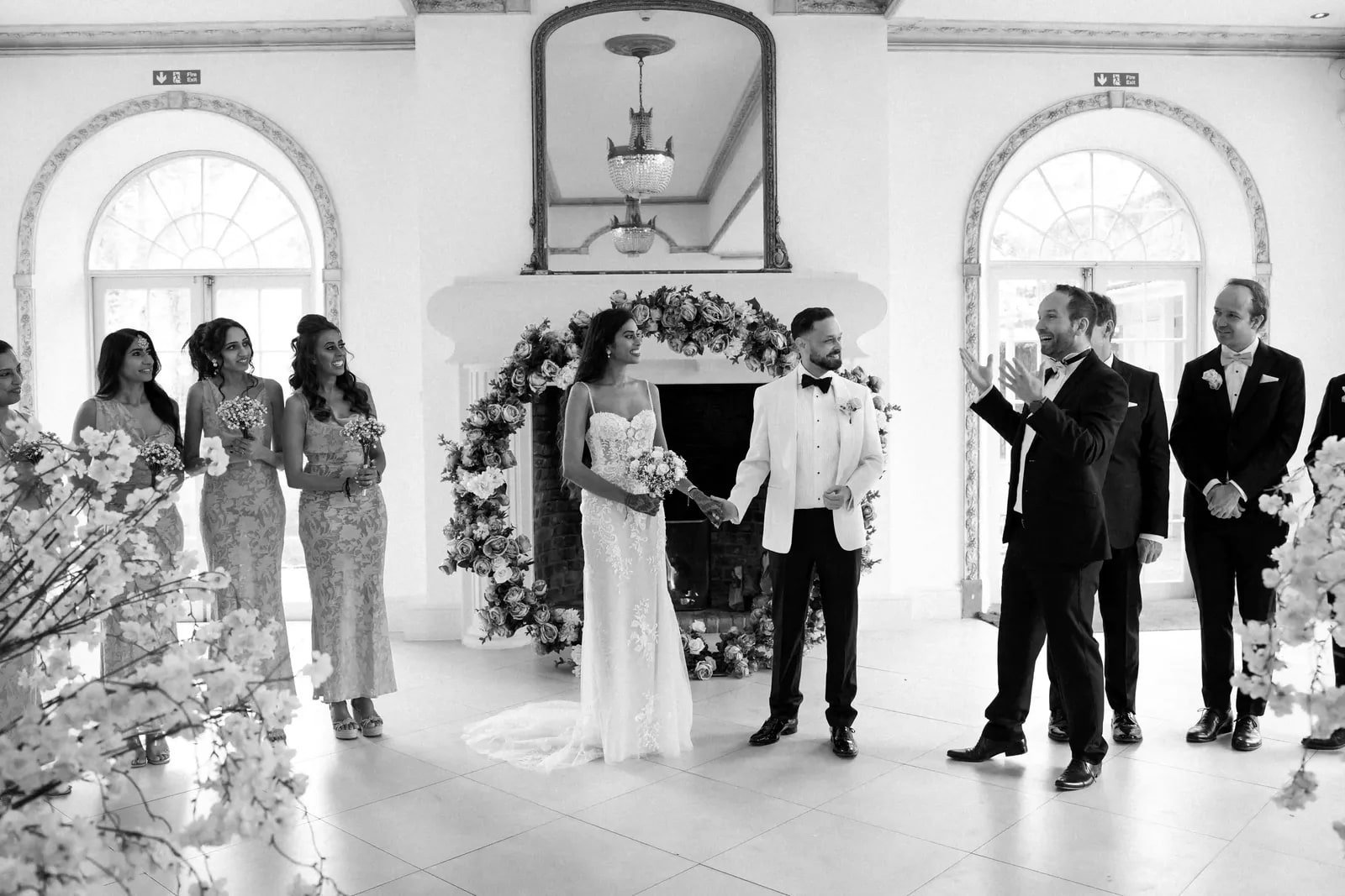 Guests applauding as the couple stand under a flowered arch in the orangery