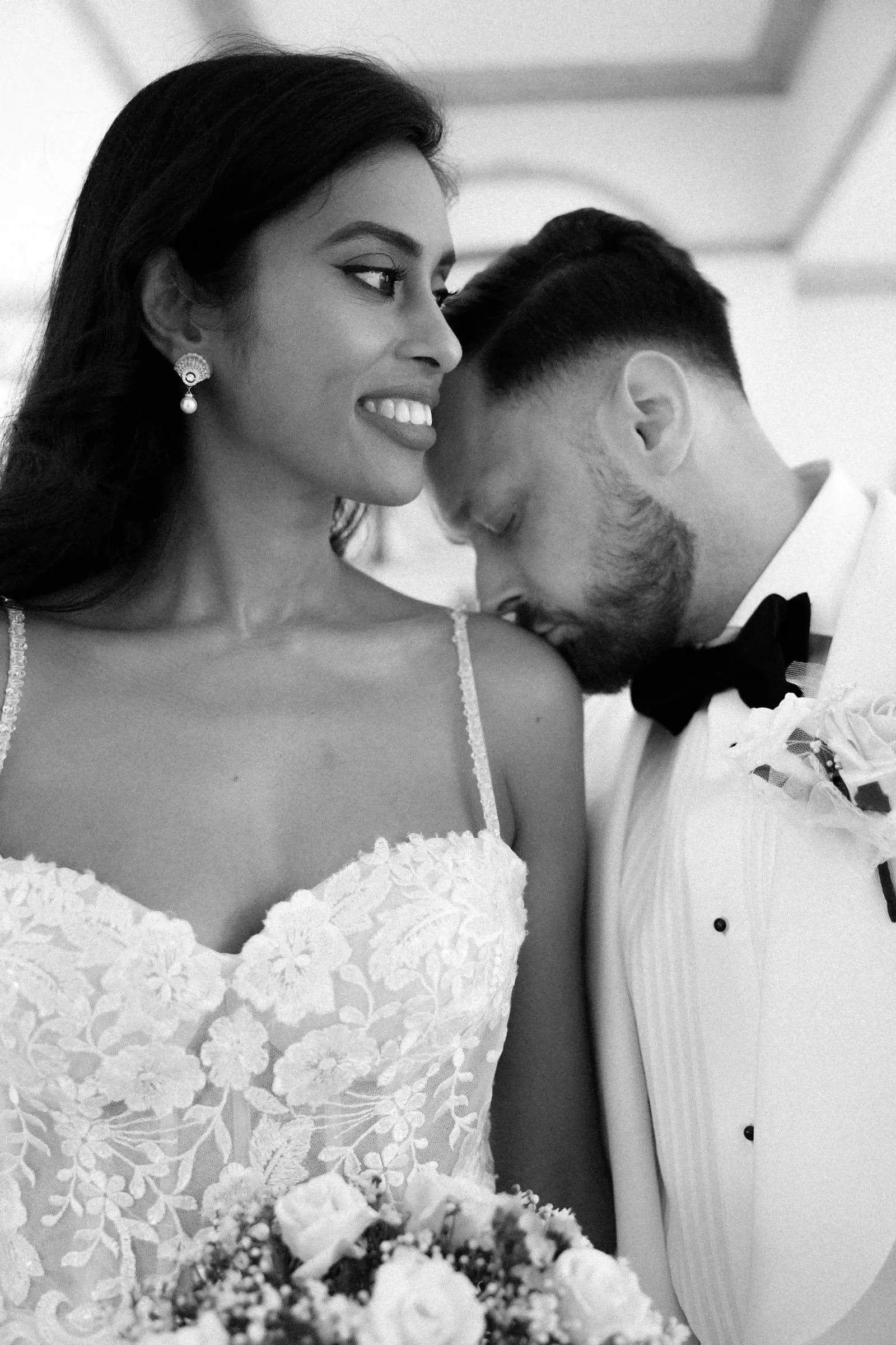 Groom leaning his head to his bride's shoulder, close and in black and white