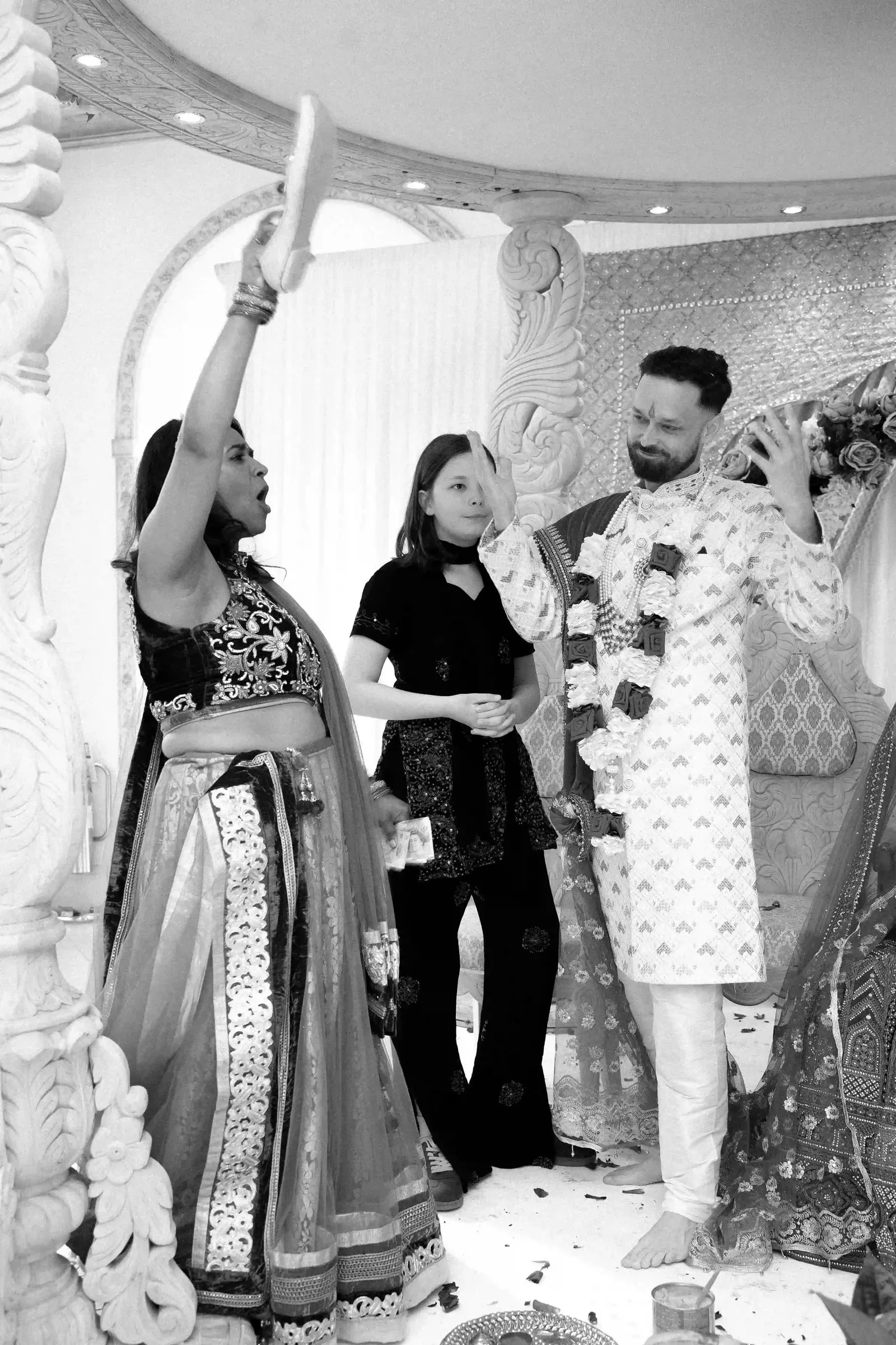 Guest raising a rolled document above the couple during the ceremony, in black and white