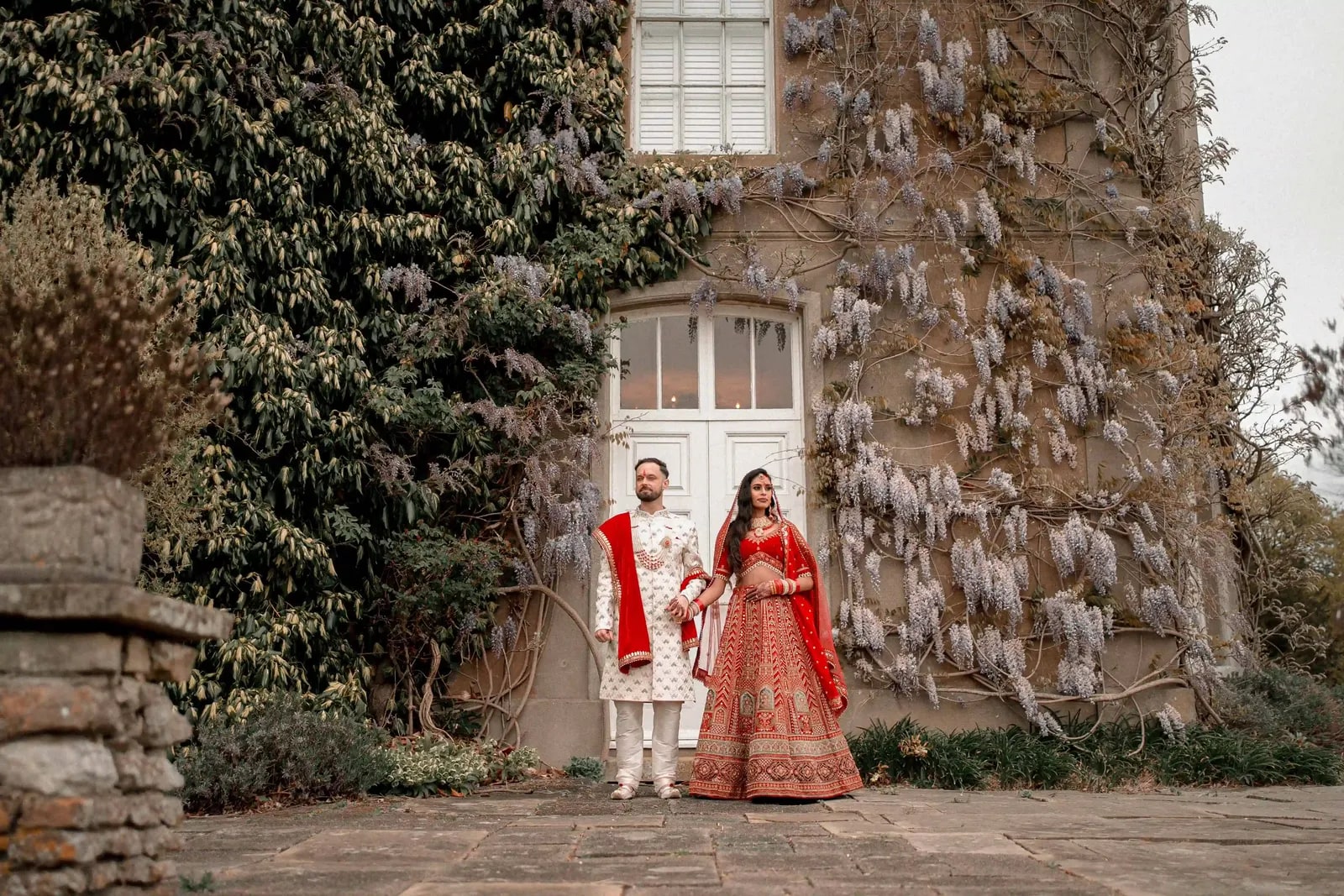 Couple in red and ivory beneath the hanging wisteria on the terrace
