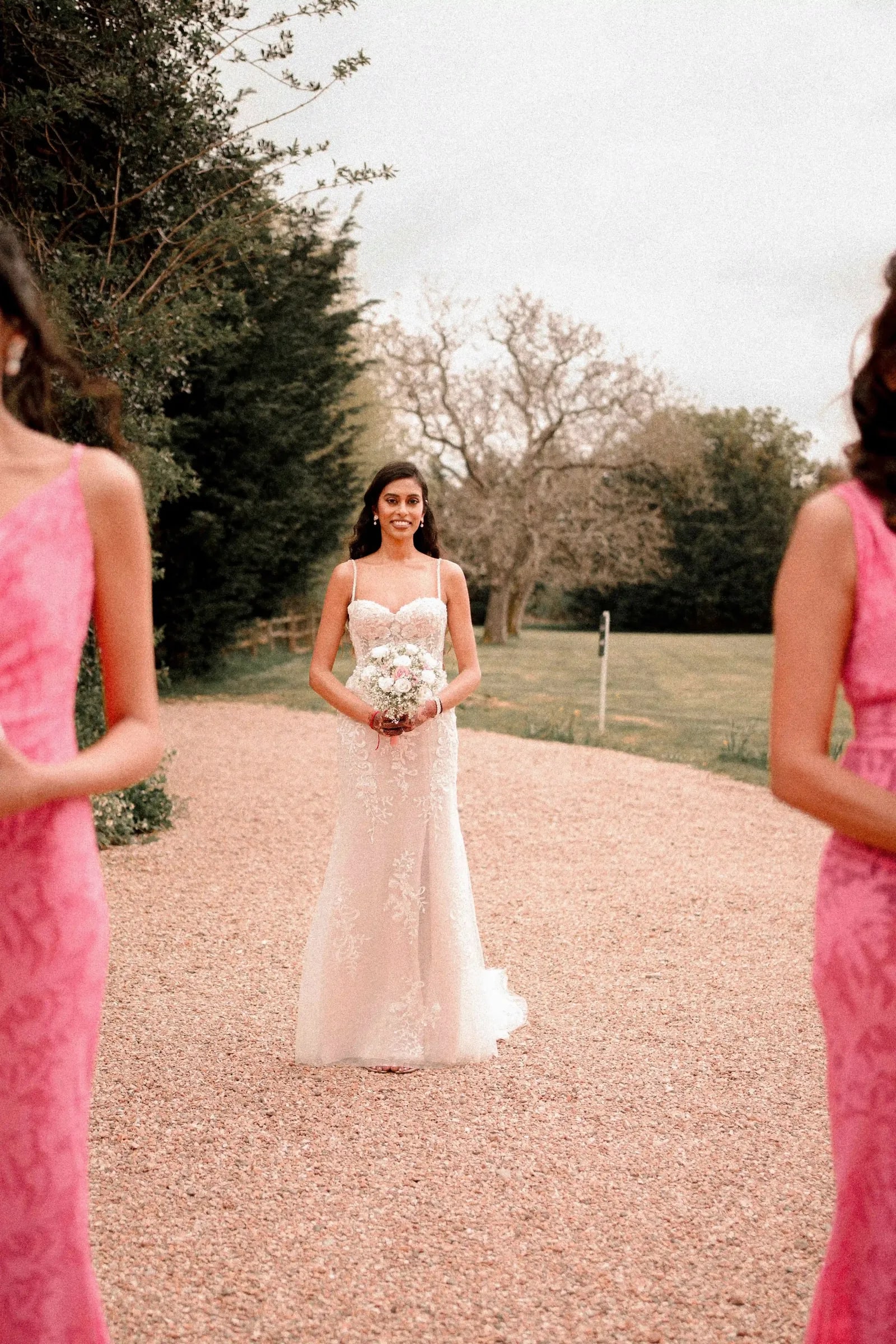 Bride in a blush gown walking towards her bridesmaids in pink