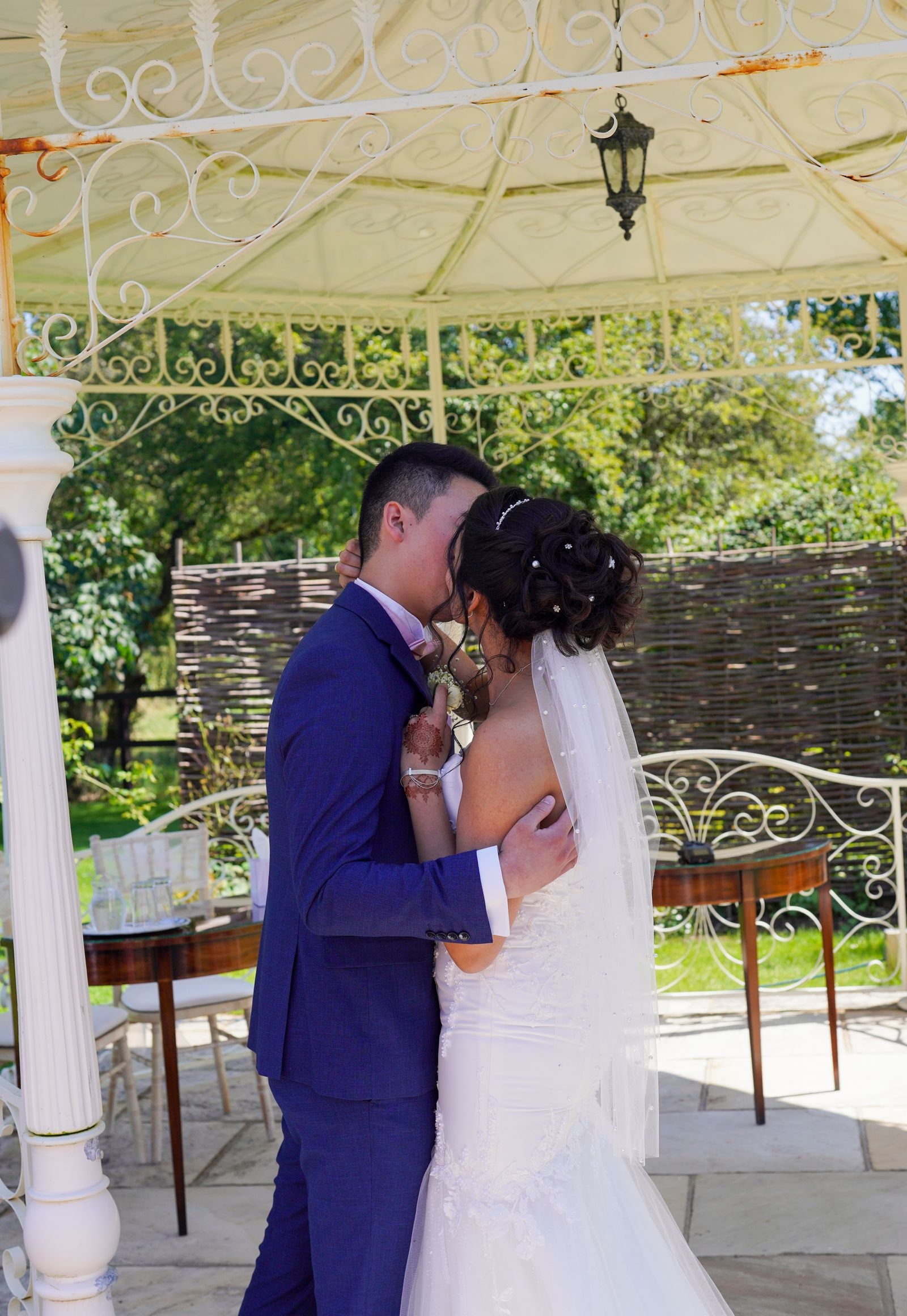 Bride and groom holding each other under the white iron bandstand
