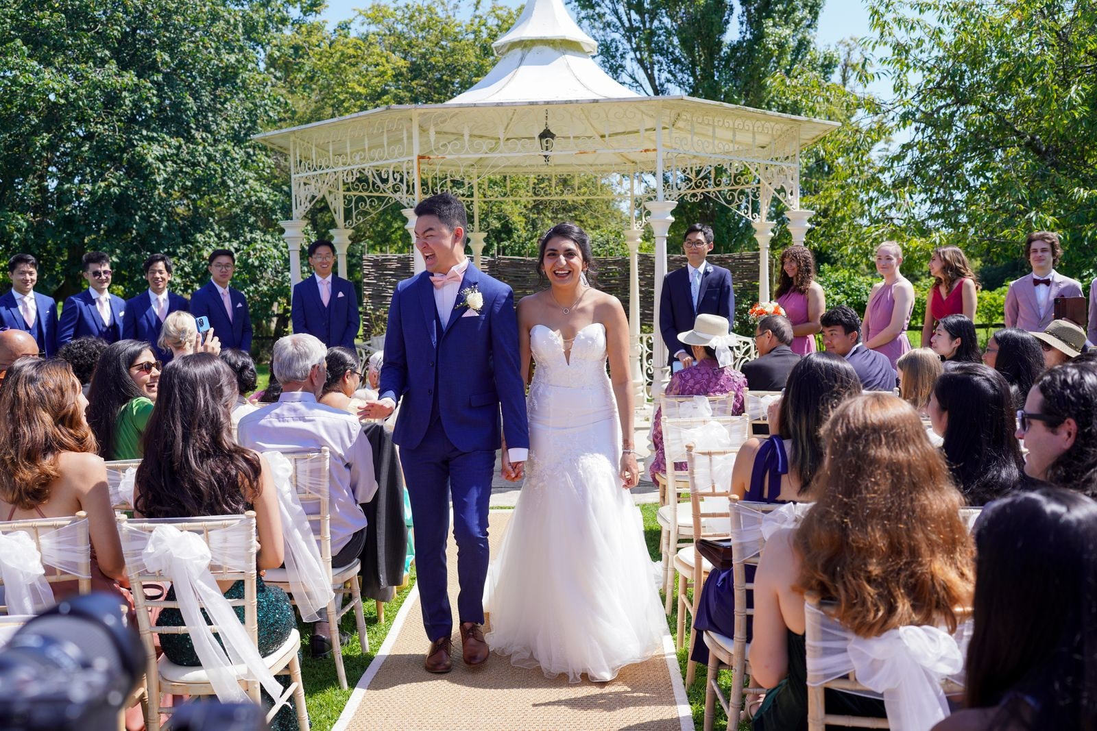 Bride and groom walking back down the aisle between seated guests after the ceremony
