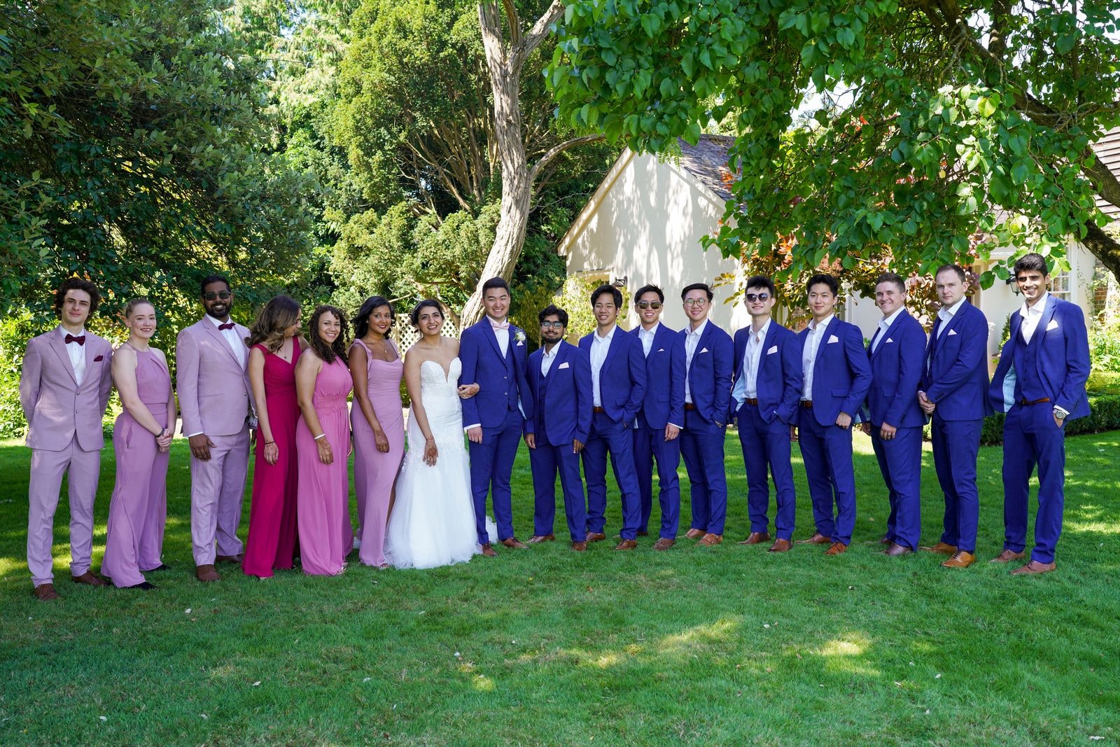 The whole wedding party on the lawn, bridesmaids in pinks and groomsmen in bright blue suits