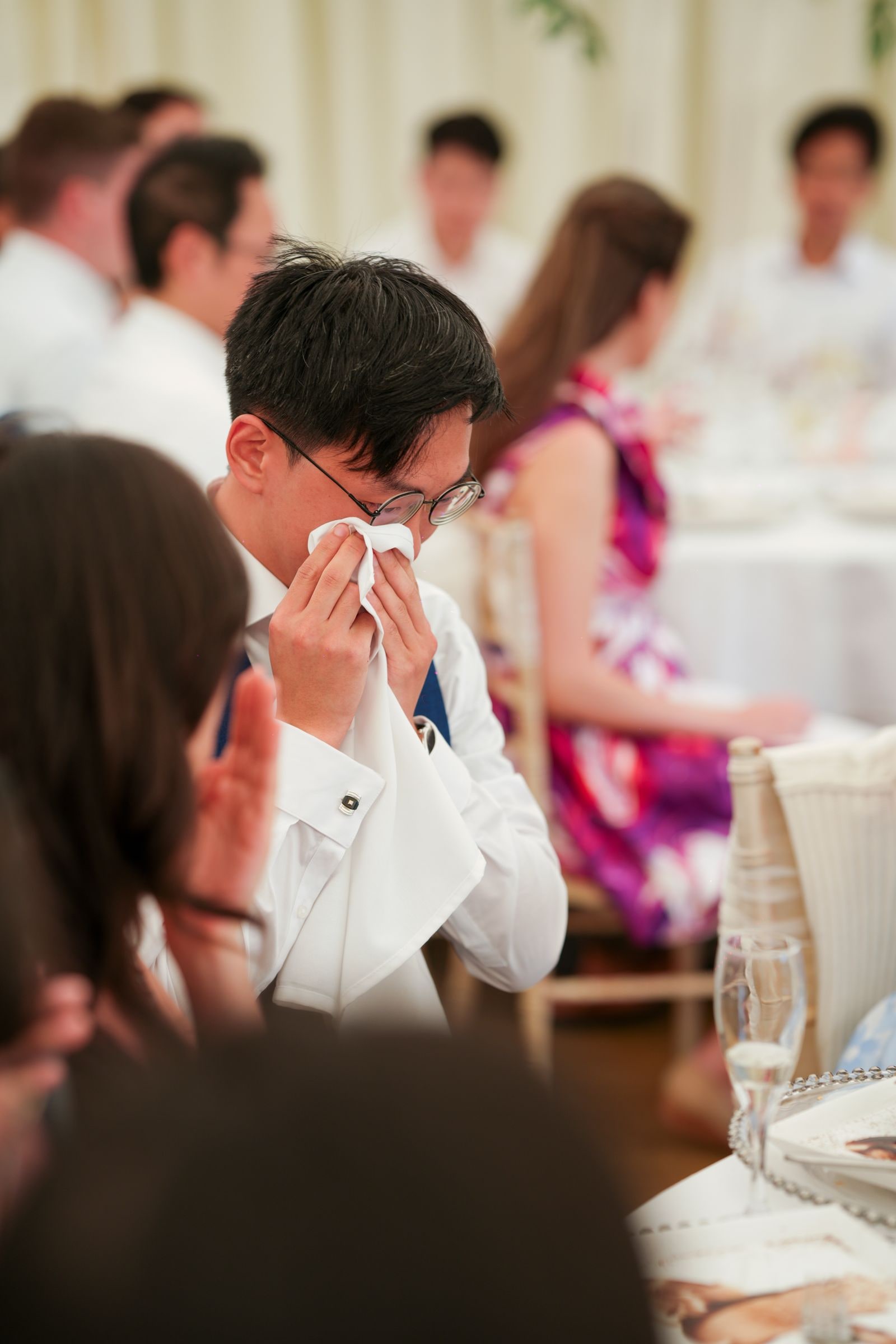 Guest holding a handkerchief to his face at the table, others listening around him