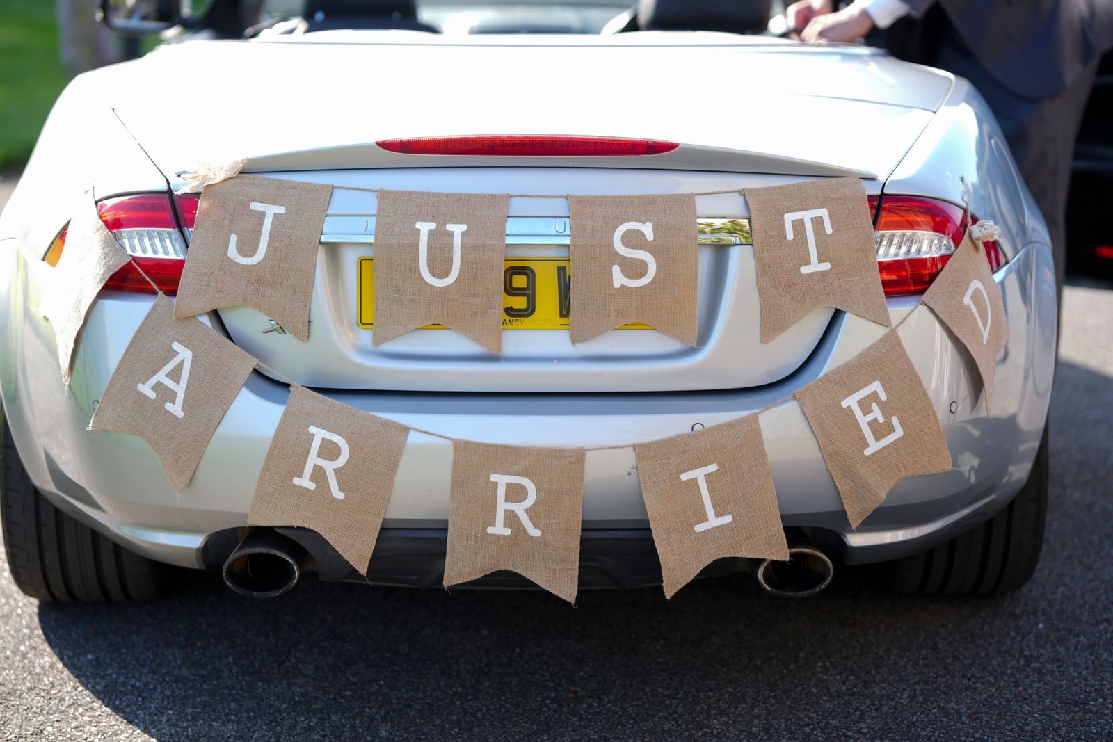 Burlap Just Married bunting strung across the boot of a silver convertible