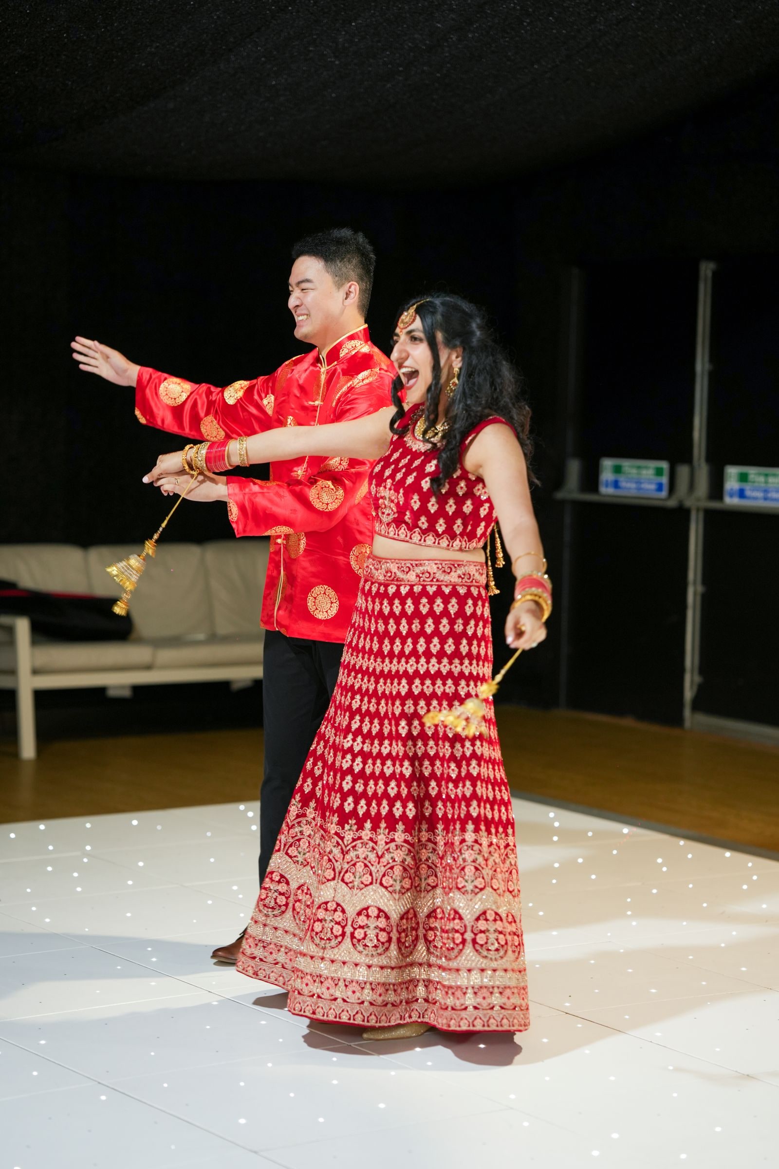 Couple dancing together on the white dance floor in red and gold outfits