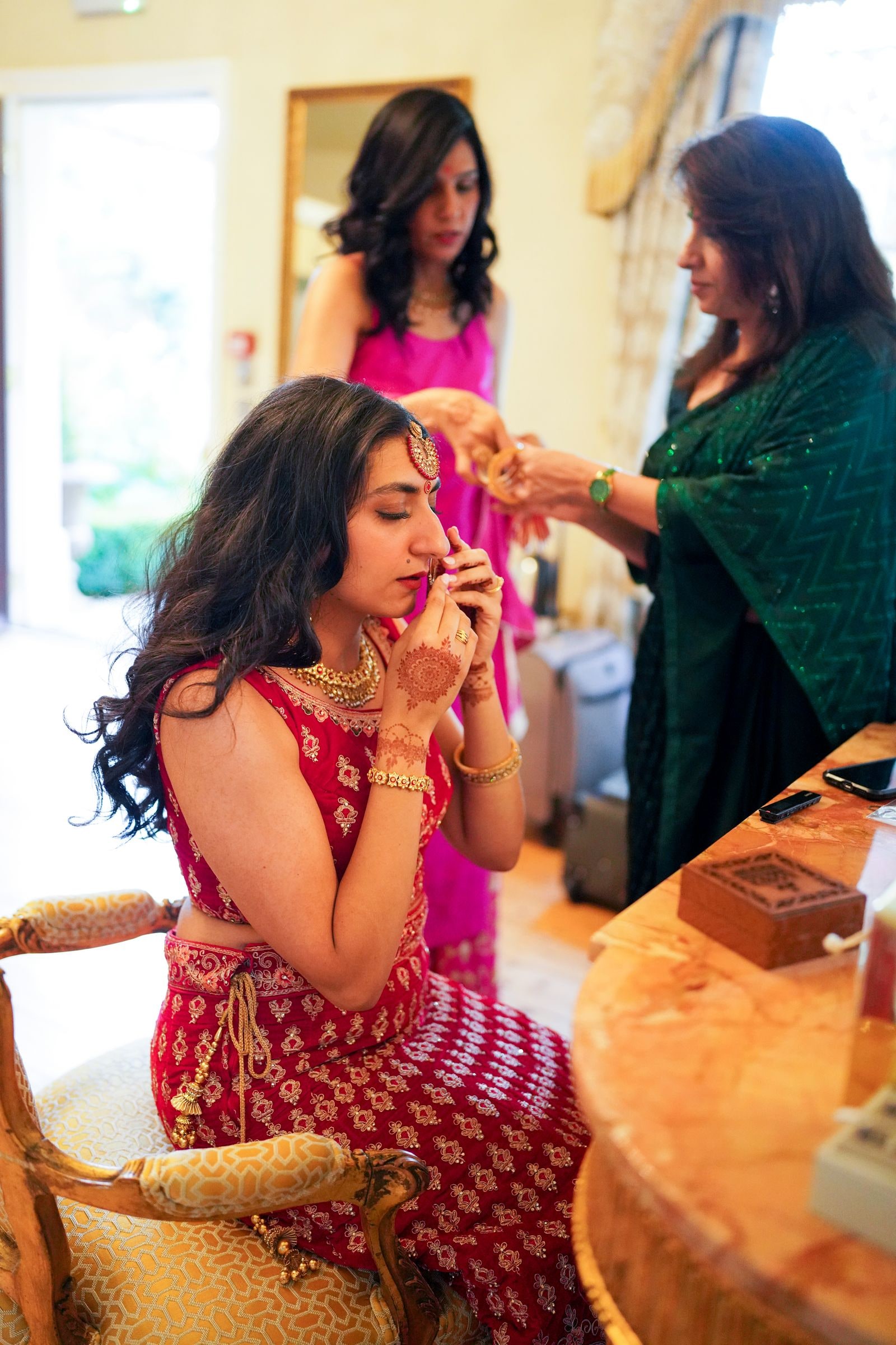 Bride being helped with her jewellery before the ceremony, two women around her