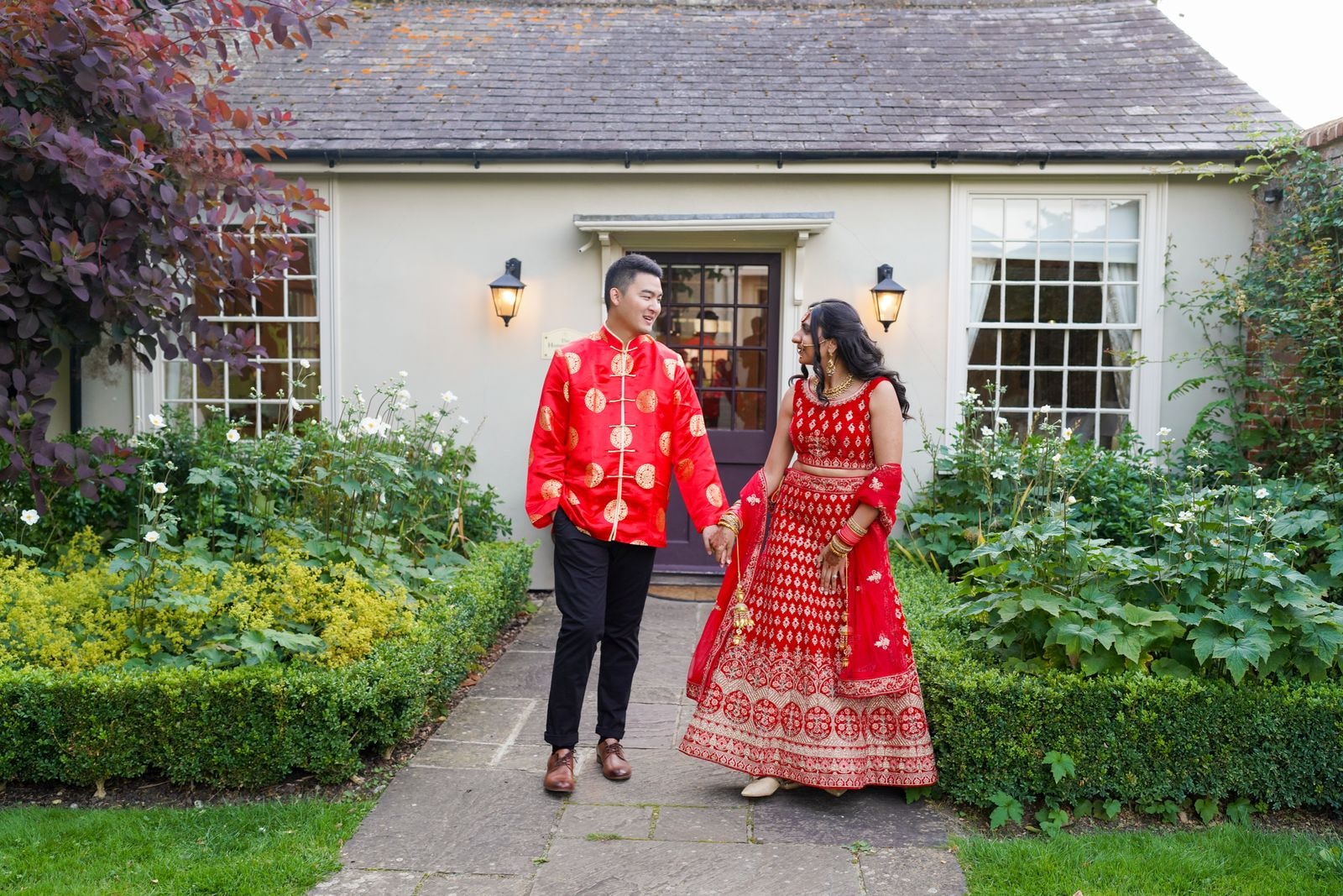 Couple in red and gold walking a garden path towards the house