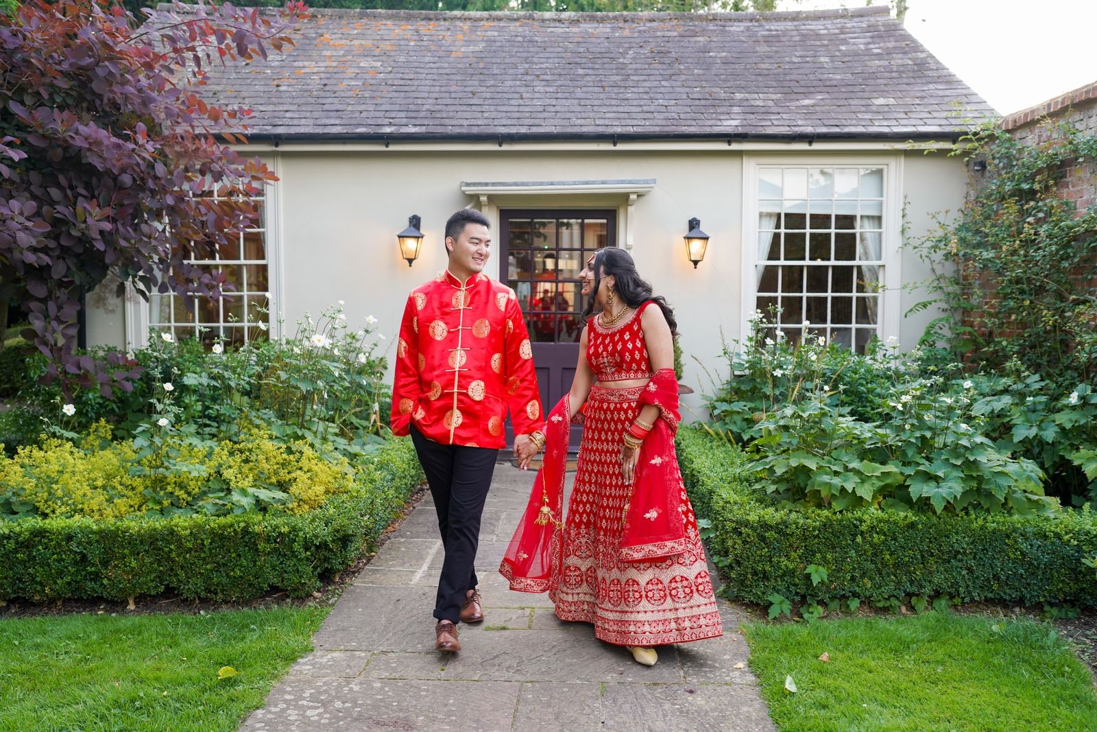 Groom leading his bride along a garden path between clipped hedges