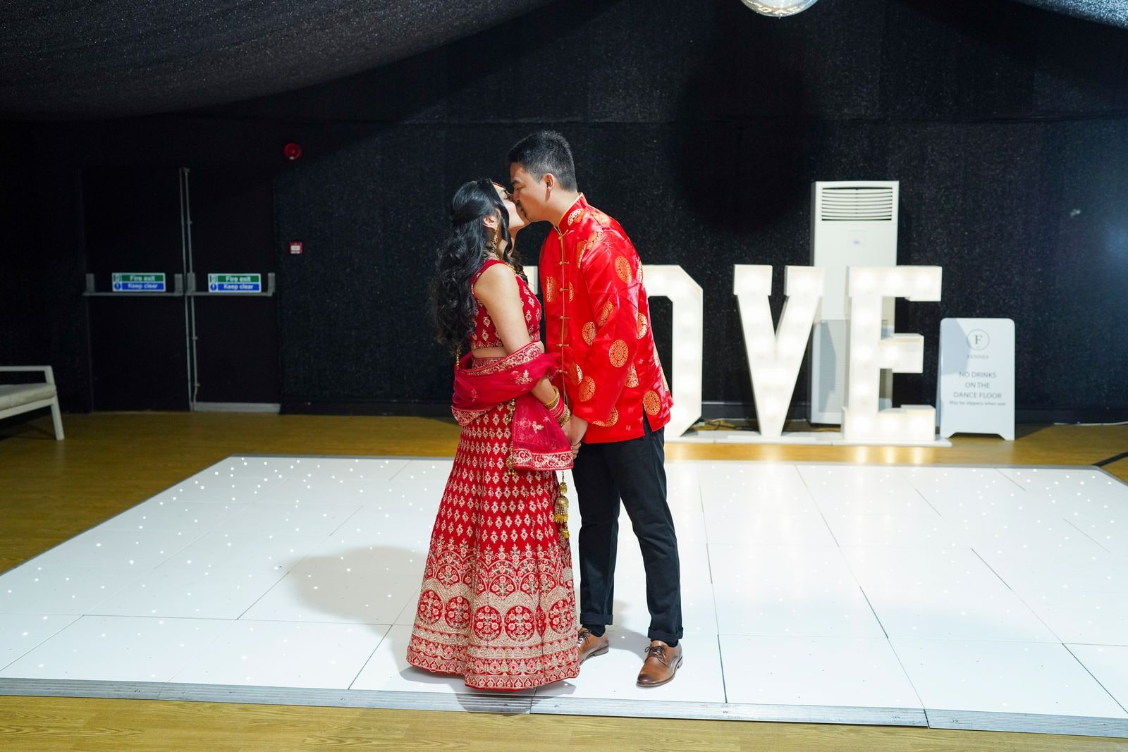 First dance on the white floor beside illuminated LOVE letters
