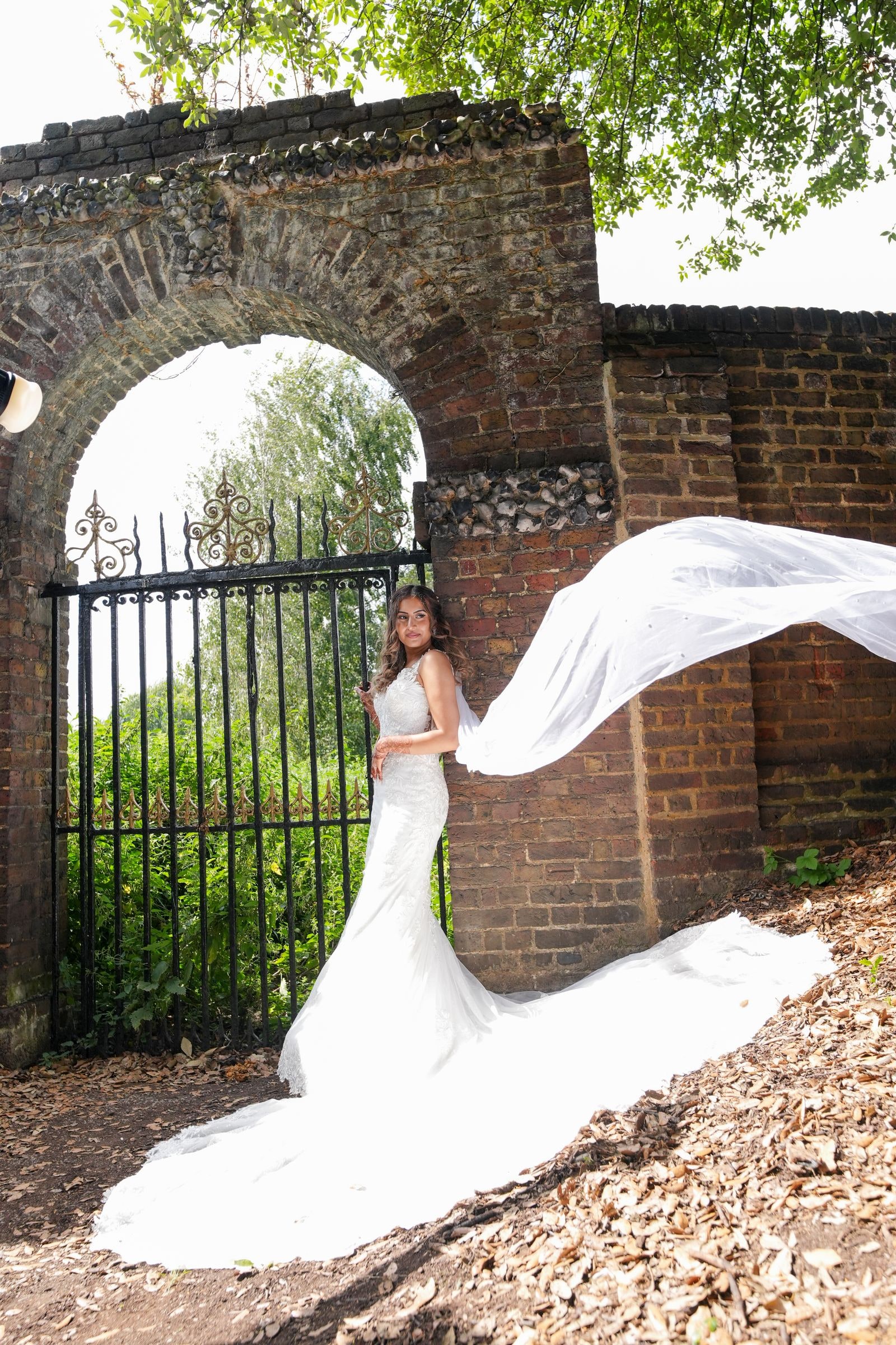 Bride in an iron gateway, her veil streaming out to one side in the wind
