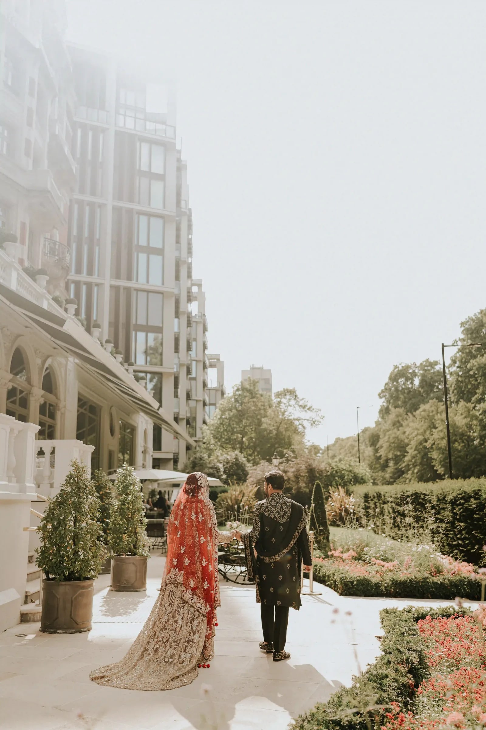 Couple walking away down a garden path, her long train sweeping the paving