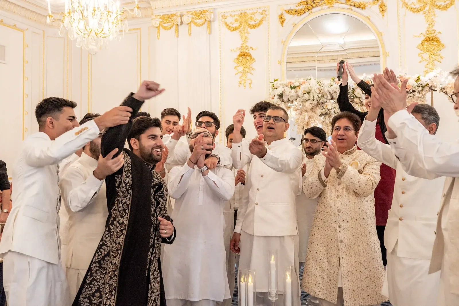 The groom's friends in ivory dancing around him in the gilded ballroom