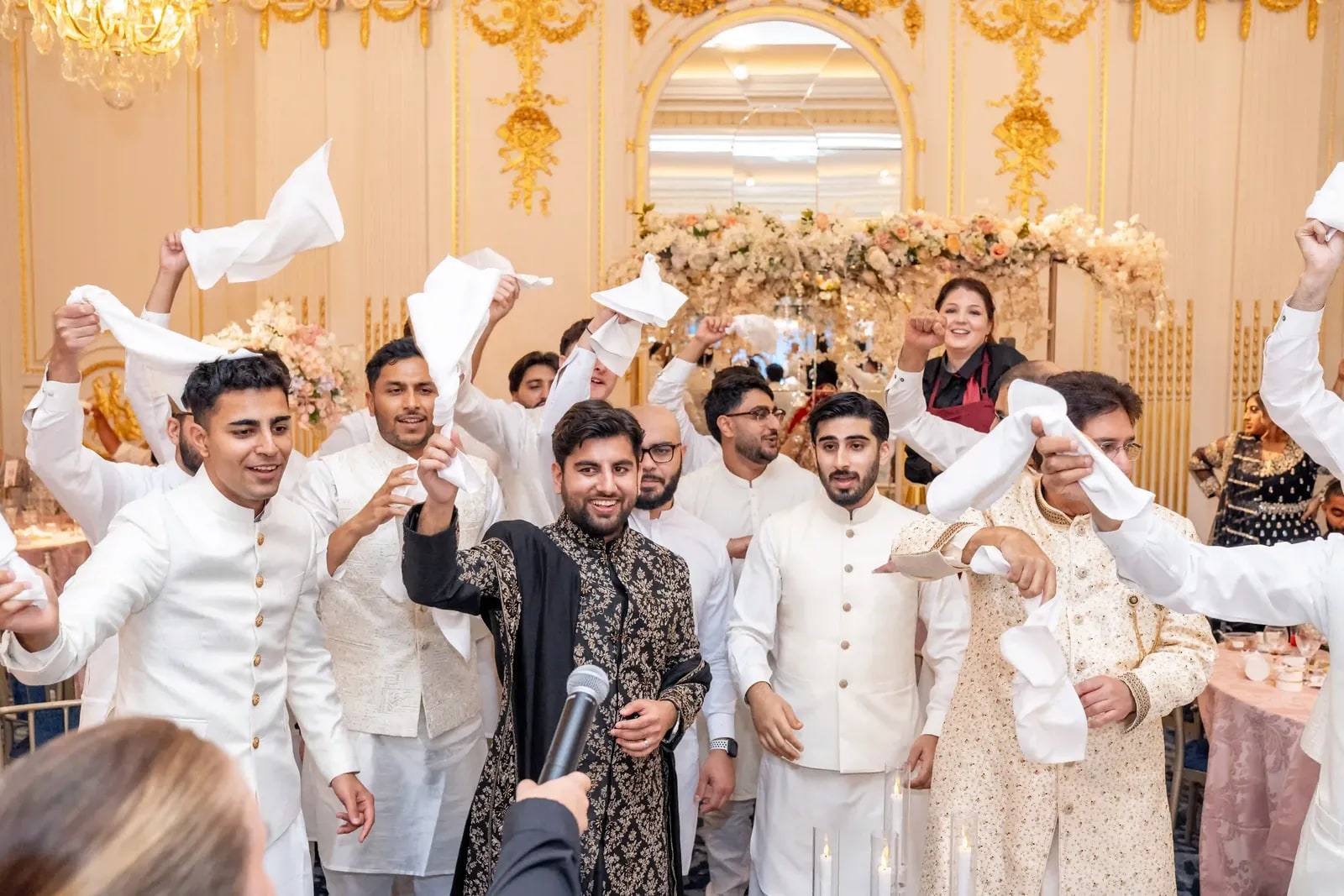 Friends waving napkins over their heads around the groom during the reception