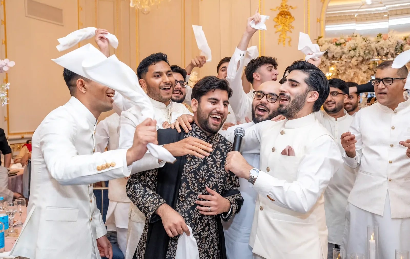 Groom laughing in the middle of his friends, napkins spinning around him