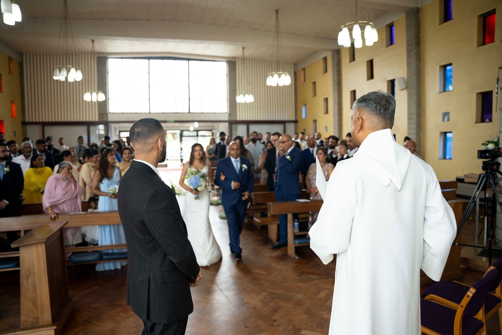 The couple walking down the church aisle, the priest watching from the front