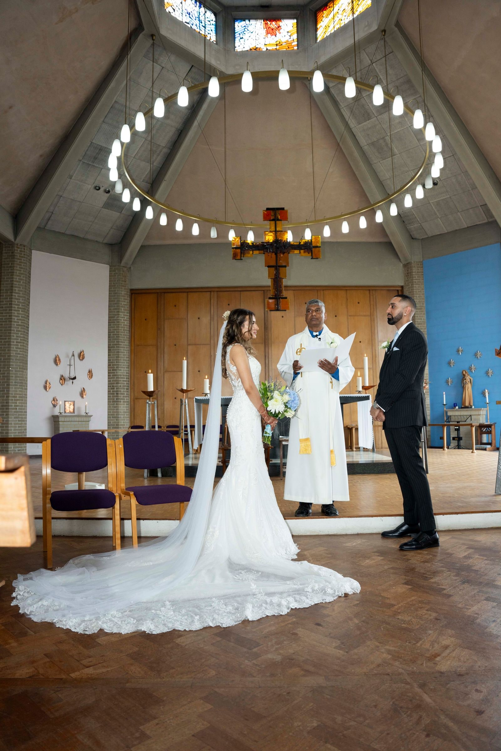 Bride and groom standing before the priest under the church's lantern ceiling