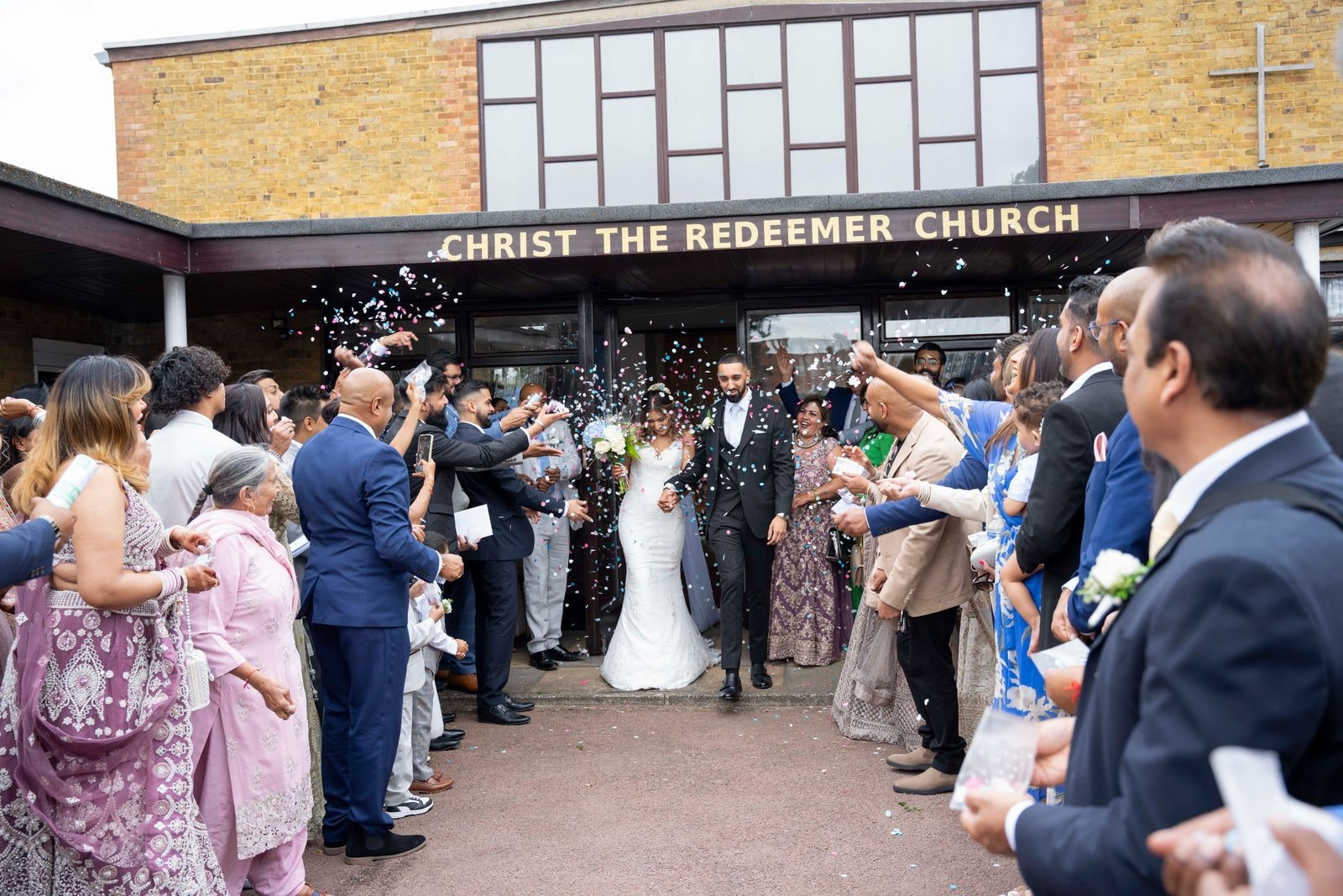Guests throwing confetti as the couple leave Christ the Redeemer Church