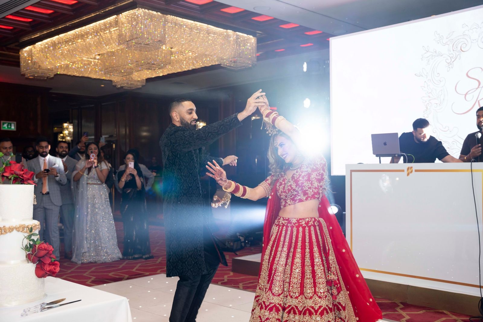 Couple dancing under a spotlight on the reception floor, guests watching