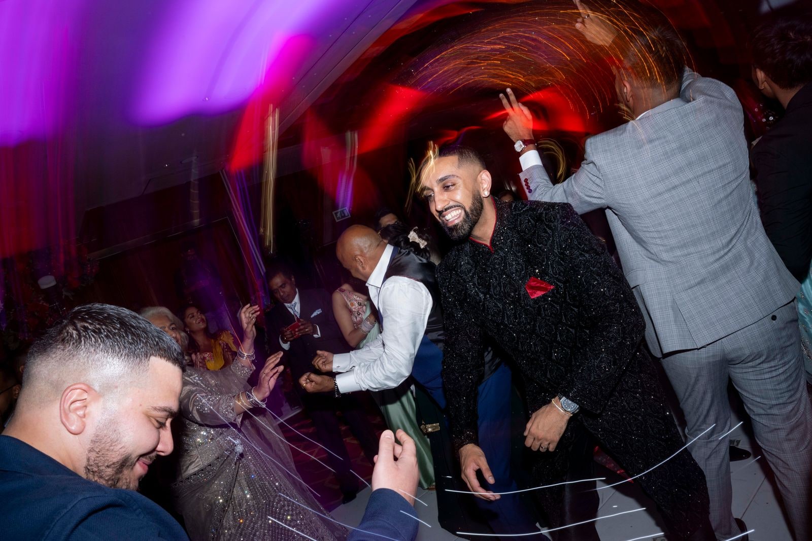 Groom singing into a microphone among the guests on the dance floor