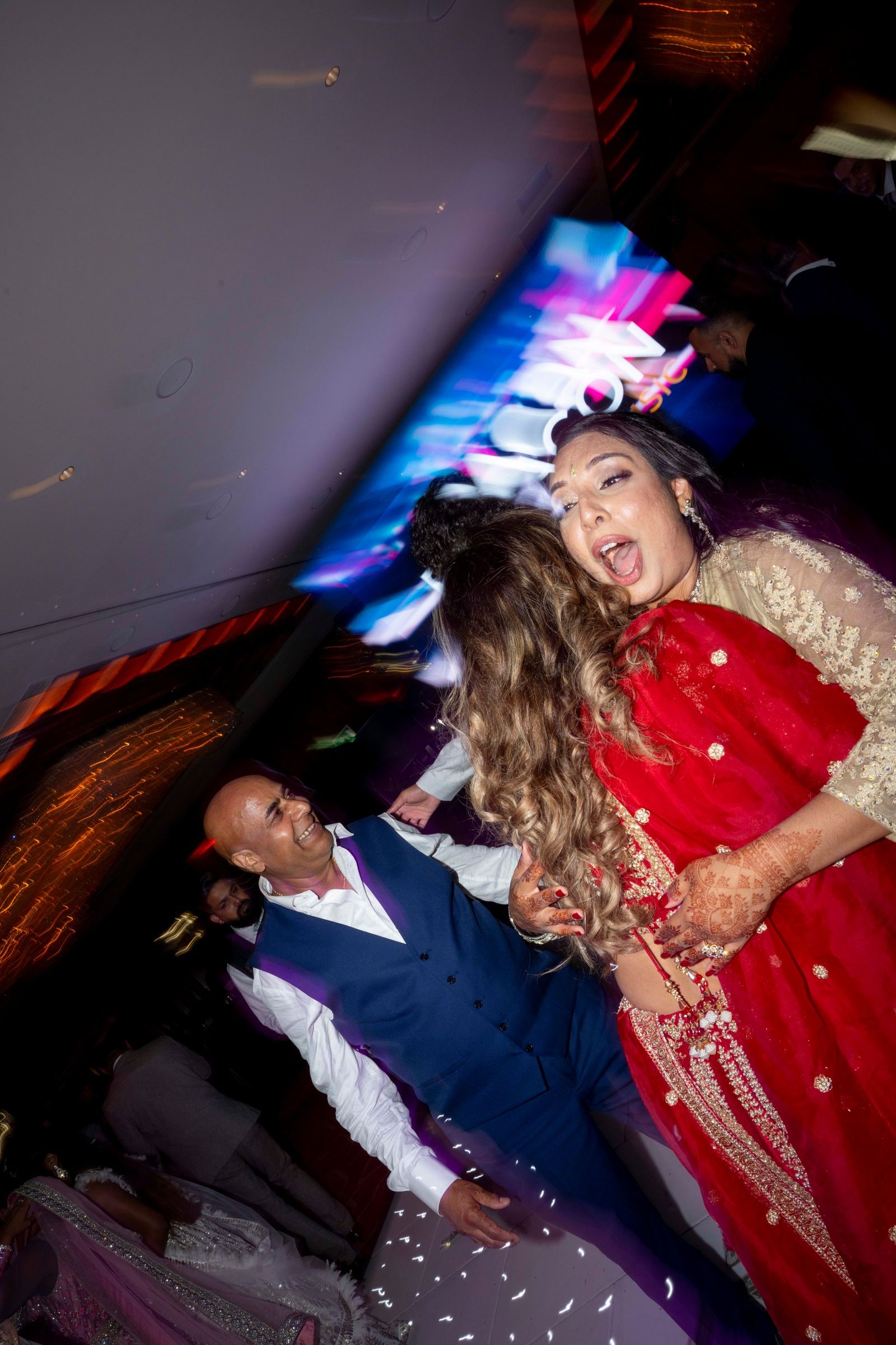 Guests dancing under purple lights, the frame tilted and blurred