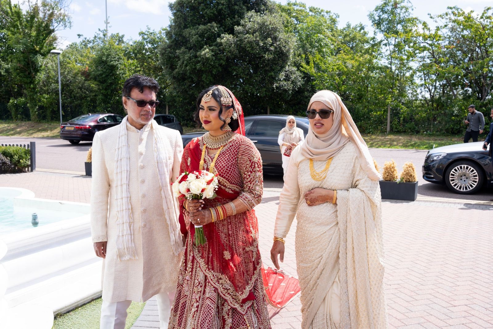 Bride walked in by her parents, her father in ivory, her mother in a cream sari