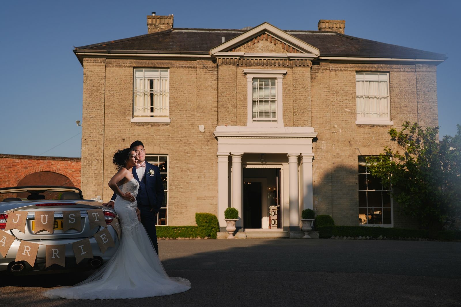 Couple embracing on the drive, the silver convertible in the foreground