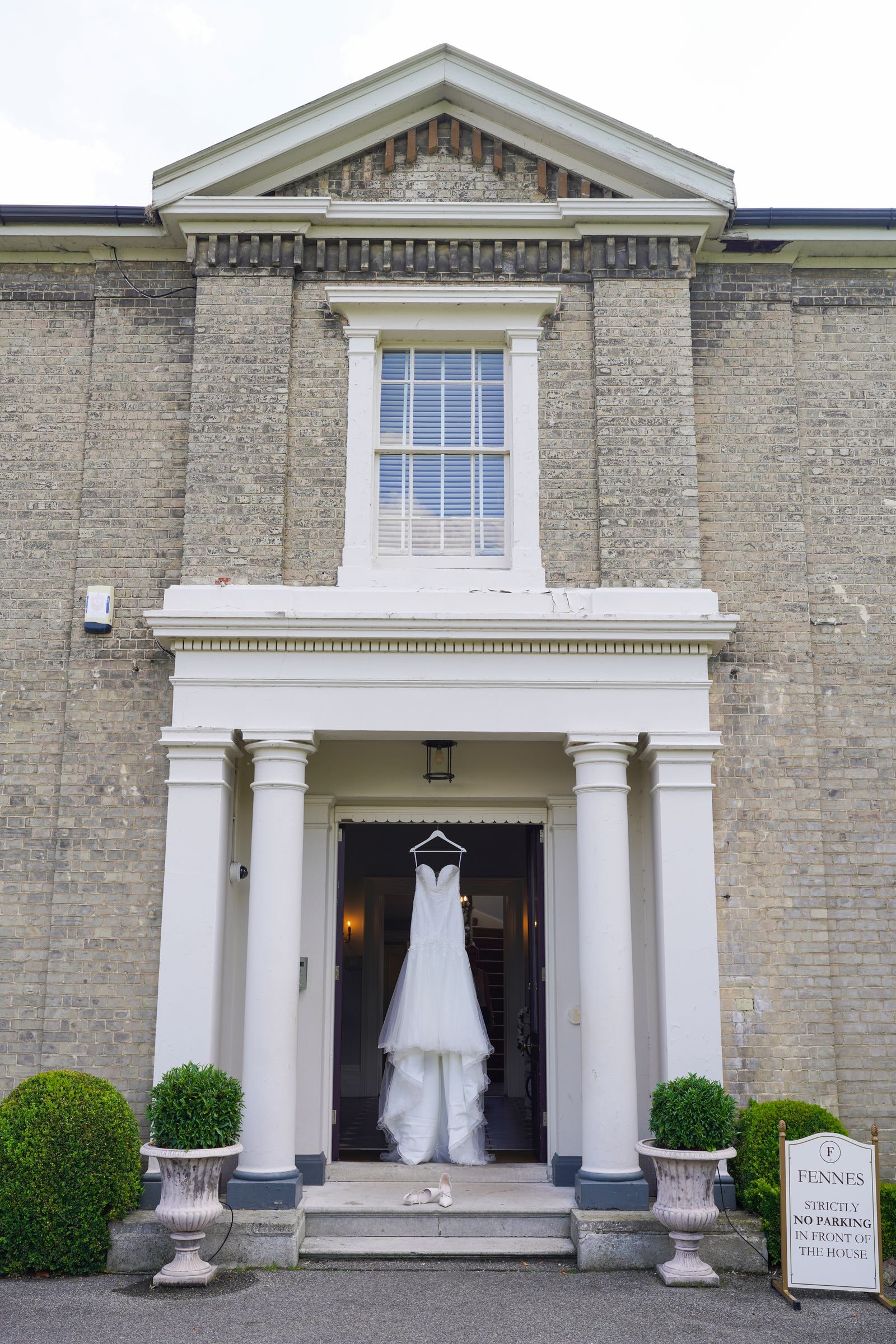 The wedding dress hanging in the pillared doorway of the house