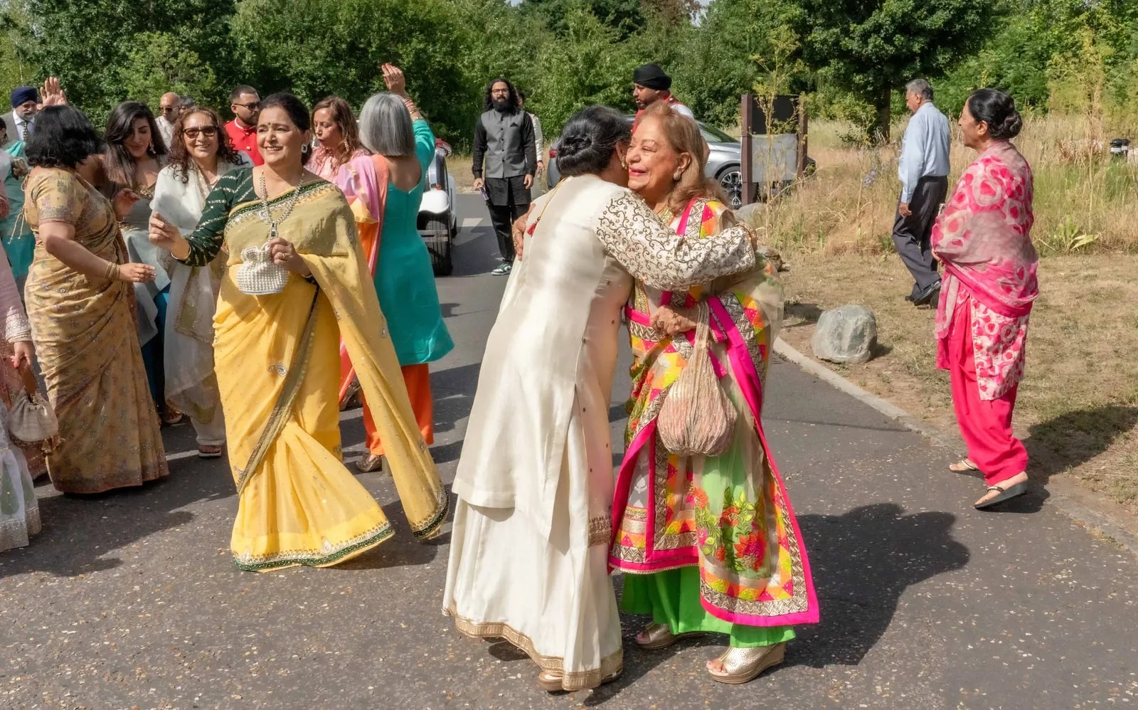 Two women embracing on the road as the guests gather for the baraat