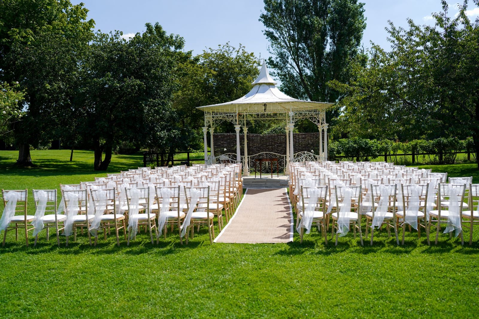 Rows of white chairs set out on the lawn facing the iron bandstand before the ceremony