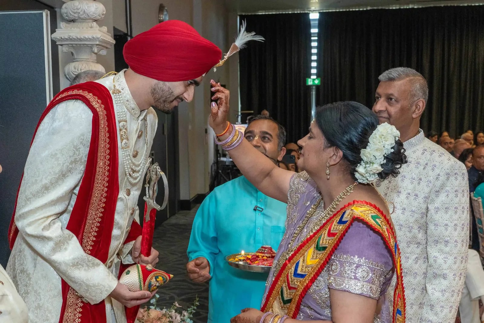 The groom's mother-in-law performing the welcome ritual as he holds a decorated stick