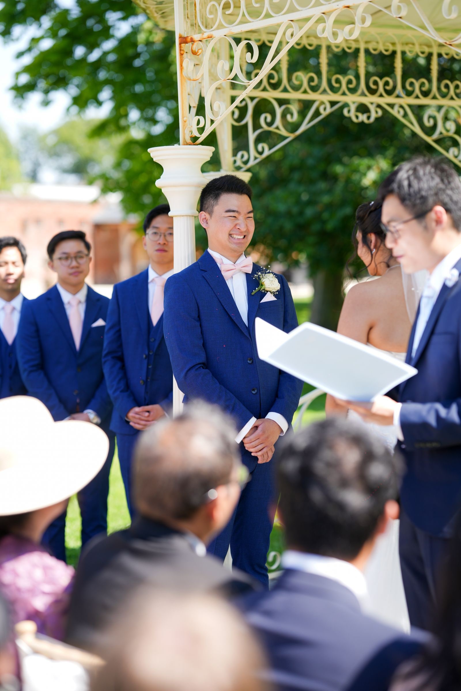 Groom and groomsmen listening as the celebrant reads, guests watching from their seats