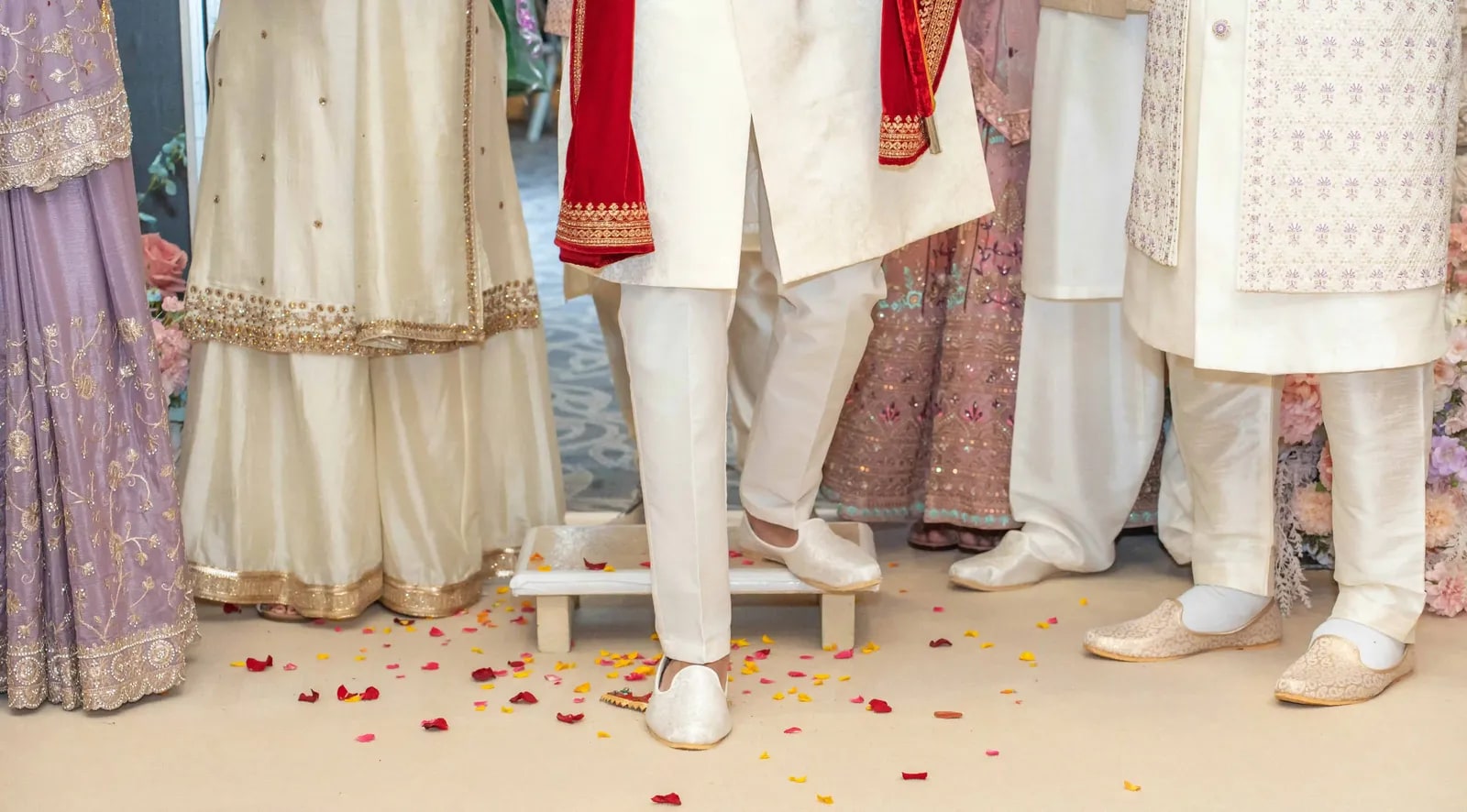 Close view of feet and hems on a petal-strewn floor during the ceremony