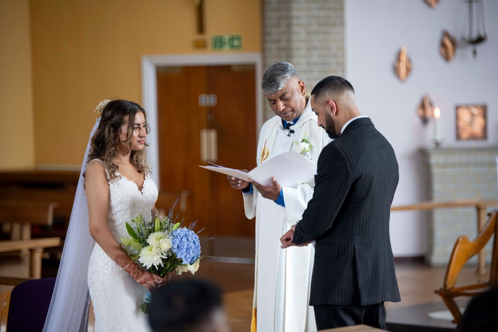 Bride and groom at the front of the church as the celebrant reads