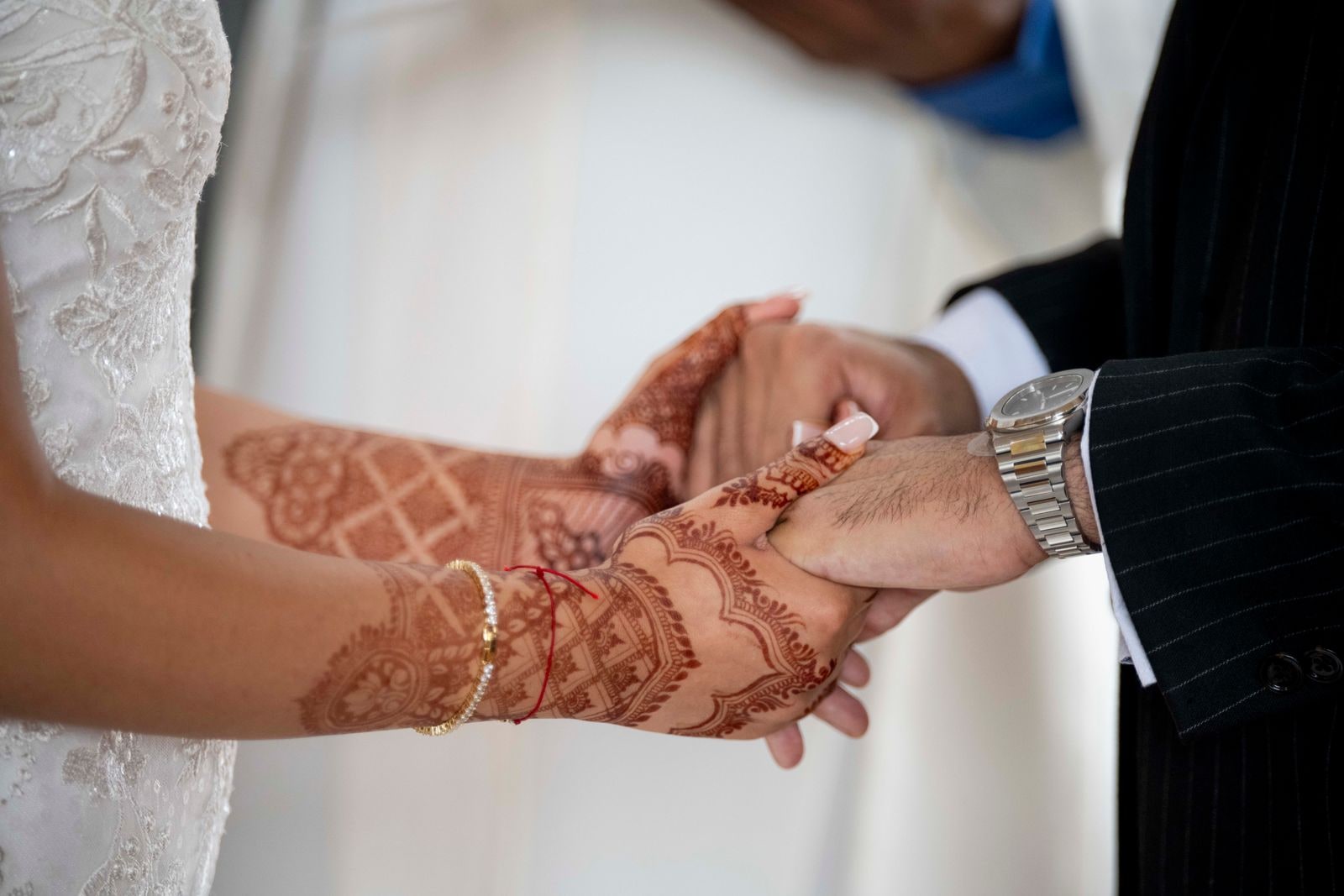 The bride's hennaed hand held by the groom during the ring exchange