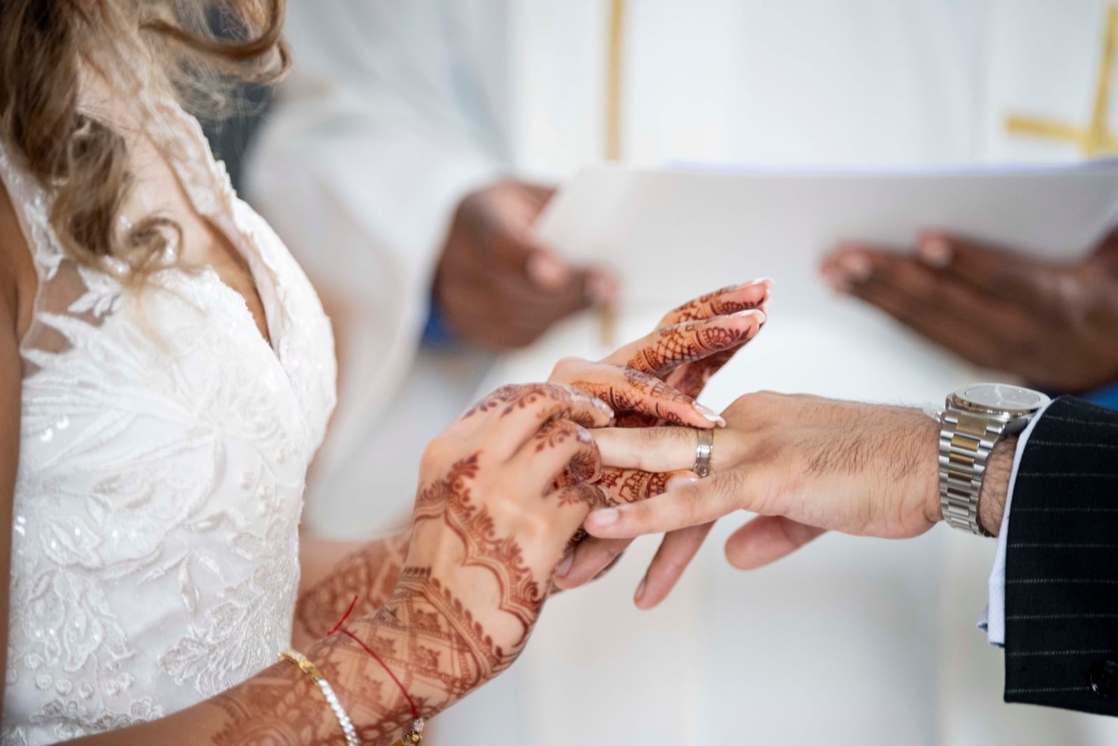 The ring being placed on the bride's hennaed finger