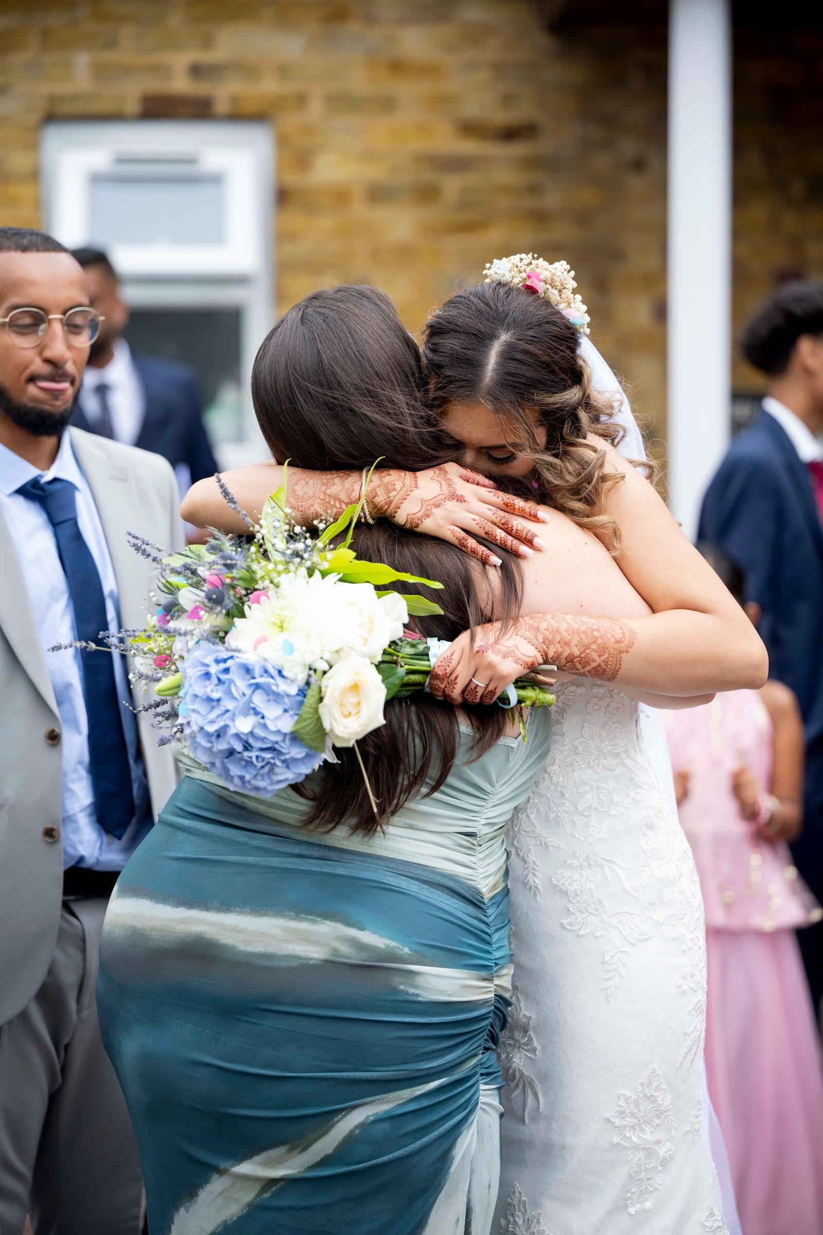 Bride embracing a guest outside after the ceremony, bouquet in hand